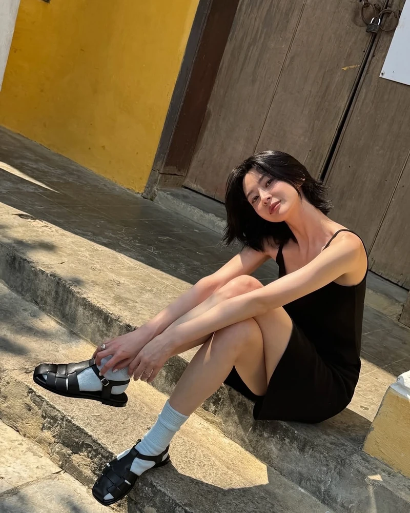 여름 양말??🤍🖤권나라 포인트 참고
다리 더 길어 보이고 싶나요?✍️여름 슈즈 양말 매치법, 4가지로 정리
여름 룩 완성은 양말이 절반입니다. 샌들이든 로퍼든 스니커즈든, 발목 위로 올라온 크루 양말 한 켤레가 다리 라인을 길어 보이게 만들고 무드까지 잡아냅니다.
1. 피셔맨 샌들 + 라이트 블루 크루 양말
여행 중 권나라는 검정 슬립 미니 원피스에 라이트 블루 양말과 블랙 피셔맨 샌들을 매치했습니다. 블랙 톤 사이로 들어온 하늘색 양말이 시선을 잡아냈어요. 26년 여름 ‘샌들+양말’ 조합의 정석입니다.
2. 블랙 로퍼 + 화이트 크루 양말
저녁에 편안한 캐주얼 무드에서는 라이트블루 쇼츠와 화이트 탱크탑에 흰 양말, 블랙 태슬 로퍼를 매치했습니다. 발목 위 양말 길이가 다리 라인을 끊어주며 프레피한 무드를 더했습니다.
3. 화이트 스니커즈 + 옐로우 컬러 양말
휴양지 룩에서는 뉴발란스 블루 티셔츠에 데님 쇼츠, 옐로우 양말과 화이트 스니커즈를 매치했어요. 화이트 베이스 코디에서 양말 한 켤레가 컬러 포인트가 됩니다.
4. 애슬레저 레깅스 + 화이트 크루 양말
카페 데일리룩에서는 그레이 맨투맨에 블랙 레깅스, 화이트 양말과 스니커즈를 매치했습니다. 양말이 레깅스와 스니커즈 사이를 끊어주며 운동복을 데일리룩으로 전환시켰어요. 이미지2
