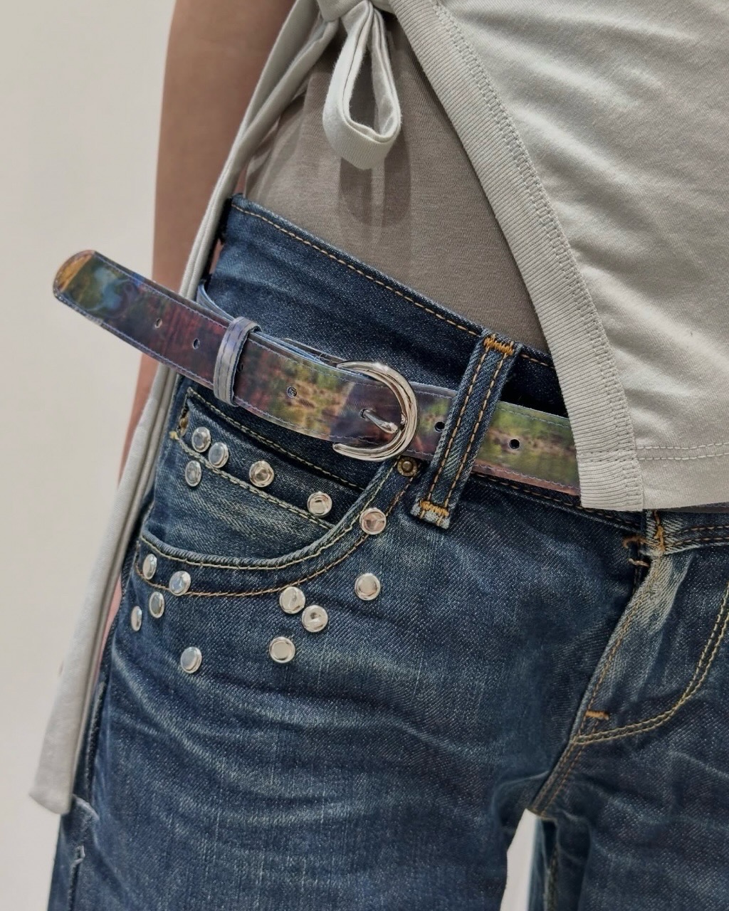 ‘움직이는 책받침’🌈🔖기억하나요?
각도마다 그림이 변하던 그 기법, 인싸 패션템입니다🩵리앤 황
LA 베이스 디자이너 리앤 황(Leeann Huang)입니다. 센트럴 세인트 마틴스(Central Saint Martins)를 거쳐 마르지엘라(Maison Margiela)·샤넬(Chanel)에서 트레이닝한 디자이너입니다.
시그니처는 렌티큘러(lenticular) 텍스타일입니다. 책받침에 쓰던 그 기법을 디자이너가 비PVC 러버 원단에 직접 인쇄해 옷·가방·벨트로 풀어낸 거예요. 걸을 때마다 색과 그래픽이 함께 움직입니다. 데드스톡·재활용 소재 소량 생산이라는 점도 강점이에요.
미니백과 벨트가 핵심 픽. 단조로운 화이트 셔츠·블랙 데님 룩에 무빙 그래픽 한 점만 얹어도, 분위기가 확 달라집니다. 이미지4