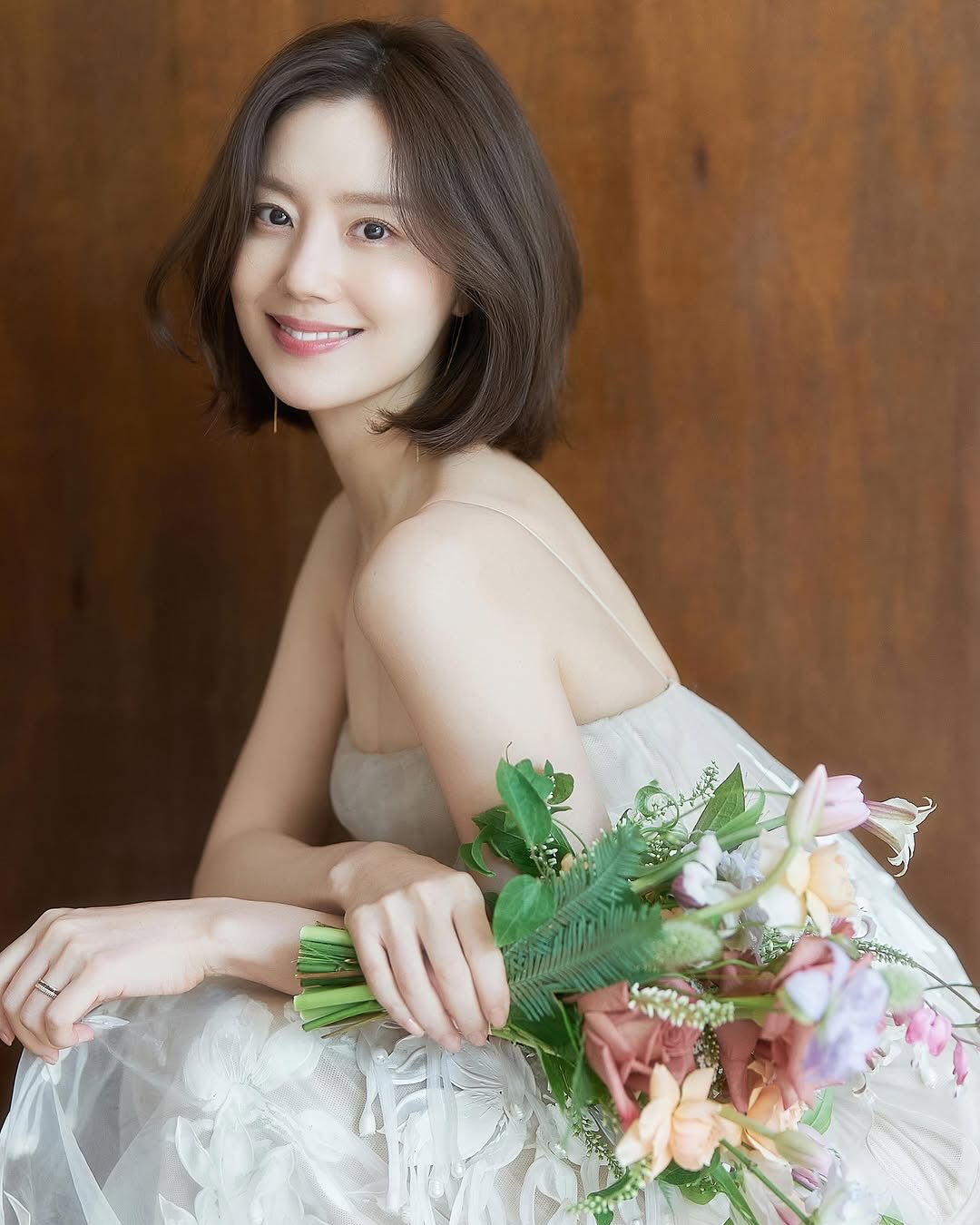 6월의 신부, 문채원 웨딩 화보👰🏻♀️
문채원이 면사포를 쓴 웨딩 화보를 추가 공개했습니다. 정교한 레이스 오프숄더 드레스에 길게 늘어뜨린 베일, 왼손 약지에는 반지가 담겼습니다. 공개 직후 댓글창은 축하로 가득 찼어요.
지난 4월 15일 자필 편지로 결혼을 알린 문채원은 이달 중 비연예인 예비 신랑과 비공개로 식을 올립니다. 이미지3