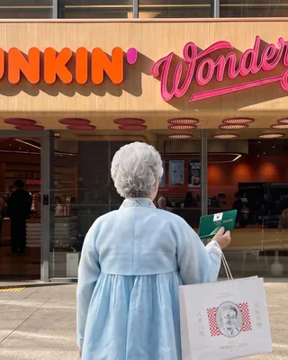 던킨 x 학화호두과자 할머니?!👵🏻🍩 “할머니, 여기서 뭐 하세요…?”, 92년 호두과자가 던킨 앞에서. 한복 차림의 할머니가 던킨 매장 앞에 서 있습니다. 손에는 학화호도과자 쇼핑백. 천안 할머니학화호도과자가 27일 공식 계정에 올린 사진입니다. 캡션은 “할머니, 여기서 뭐 하세요…?” 그리고 날짜 하나. 2026년 9월 1일. 브랜드 얼굴은 창업주 심복순 씨입니다. 남편 조귀금 씨와 1934년 문을 열어 올해로 92년, 지금은 4대째가 가업을 잇습니다. 천안 광덕면 호두와 흰 팥으로 만든 과자는 충청남도 전통문화의 집 인증 제1호를 받았어요. 학화가 던킨을 직접 언급하지는 않았습니다. 다만 공식 계정이 티저 배경과 함께 9월 1일에 확인된다고 합니다. 이미지