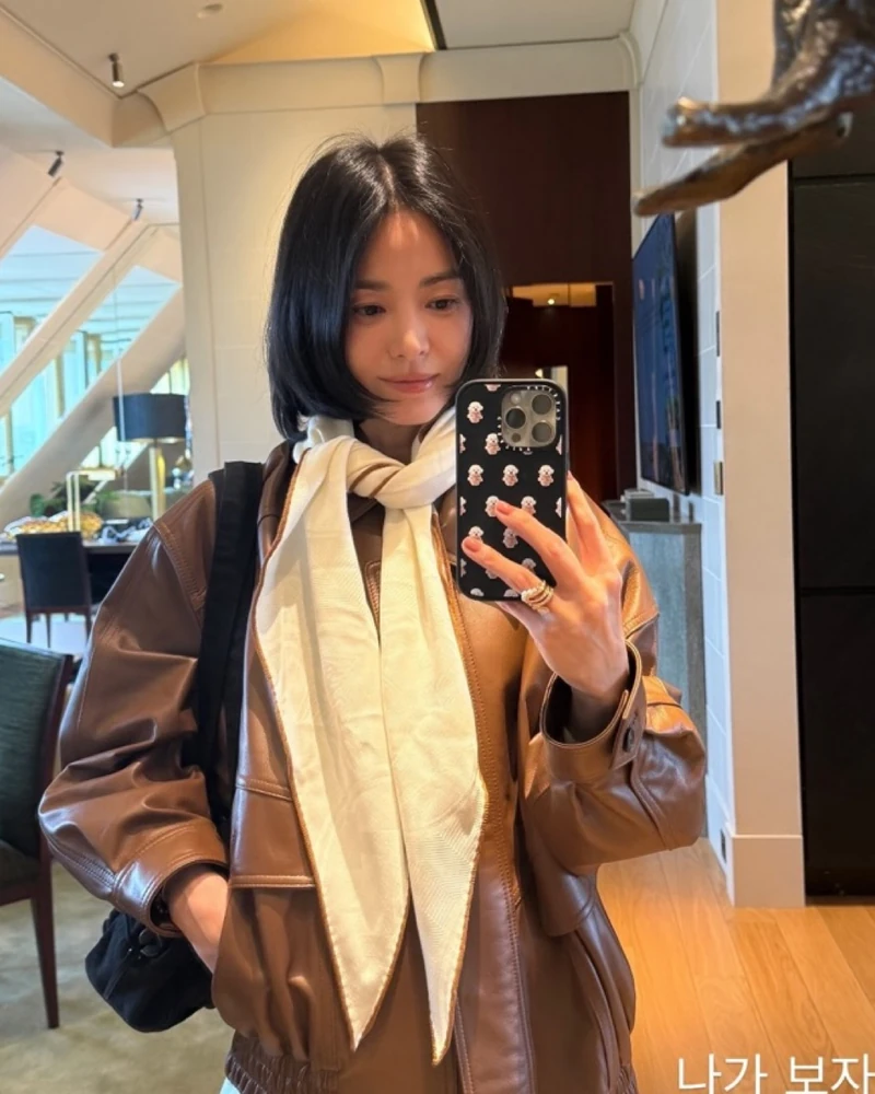 송혜교가 계절마다 쓰는🧡🤍스카프
가을엔 아이보리 로장지, 여름은 그린 반다나🧣에르메스 스카프 2장
가을 그녀는 브라운 램스킨 블루종에 아이보리 스카프를 목에 두 번 감은 룩을 했어요. 에르메스(HERMÈS) 'New Libris 로장지'로, 마름모꼴이라 목에 감으면 뾰족한 두 끝이 앞으로 떨어집니다. 같은 날 서점과 갤러리에선 풀어서 블랙 숄더백 스트랩에 리본처럼 묶었죠.
여름엔 에르메스 다른 스카프를 다르게 썼어요. 7월 크로셰 톱에 데님을 입은 날 그린 '레 토르튀 반다나 55'를 허리춤에 묶었는데, 거북이 무늬가 든 작은 사이즈라 허리나 가방 손잡이에 감는 쪽이 맞아요.
여름 반다나가 장식이었다면 가을 로장지는 기능이 먼저예요. 코트를 꺼내기 전 마지막 한 장으로 아침엔 목에 감고 낮엔 풀어 가방에 묶는 것까지가 송혜교식 간절기 대응이니, 캐시미어 혼방 마름모꼴 스카프 한 장으로 참고하세요.
• 에르메스 New Libris 로장지, 164만 원대
• 에르메스 Les Tortues 반다나 55, 48만 원대 이미지1