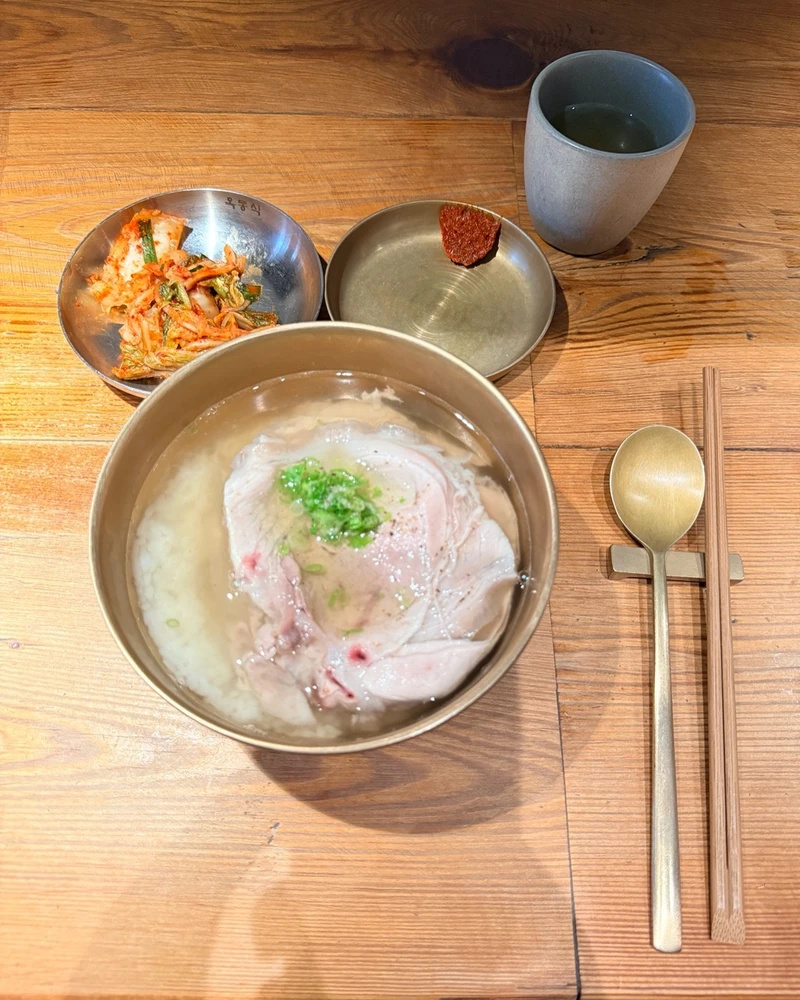 BTS도 두 번 왔다는 뉴욕 그 집🐷
뉴욕 맨해튼 돼지곰탕 '옥동식'🍚 지드래곤 자리에 앉았다
지드래곤이 앉았던 자리에 앉아봤습니다. 지난 8일(현지시간) 뉴욕·뉴저지 공연을 사흘 앞둔 밤, 수행원들과 늦은 저녁을 먹고 갔다는 소식을 듣고 곧장 따라간 참입니다. 맨해튼 매디슨가의 옥동식 뉴욕점입니다.
다녀간 사람이 지드래곤만은 아닙니다. 방탄소년단은 올해만 두 번 왔습니다. 3월 23일 스포티파이 이벤트를 마친 진·RM·제이홉·뷔 네 명이, 7월 20일에는 월드컵 결승전 하프타임 쇼를 끝낸 여섯 명이 이 국밥집에 들렀습니다.
메인 메뉴는 돼지곰탕 입니다. 2022년 넉 달짜리 팝업으로 뉴욕에 상륙했다가 정식 매장을 냈고, 뉴욕타임스는 2023년 "맑고 황금빛 돼지고기 육수"라며 올해 최고의 요리로 꼽았습니다. 서울 본점은 2018년부터 8년 연속 미쉐린 가이드에 올라 있습니다.
국밥 한 그릇 먹겠다고 맨해튼에서 줄을 섰습니다. 이미지2