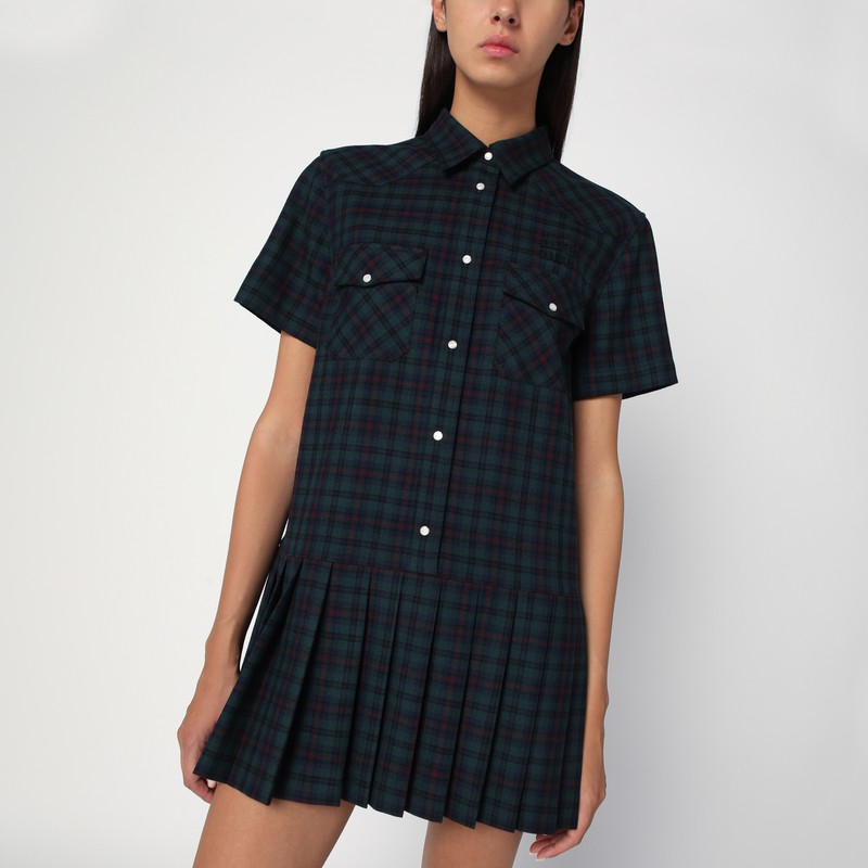 미우미우의 버진 울 소재 숏 드레스는 블루와 그린 타탄 패턴, 클래식 칼라, 앞 단추, 가슴 부분에 단추가 달린 플랩 포켓, 가슴 부분에 로고 자수가 특징입니다. 이미지