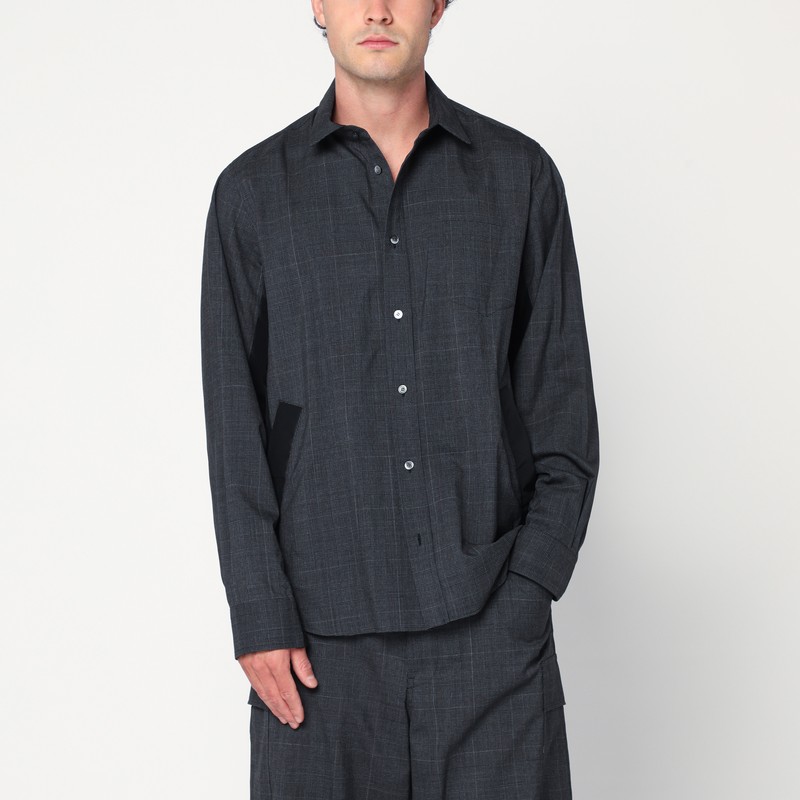 Sacai의 회색 울 셔츠 자켓은 체크 패턴, 기술 소재의 측면 패널, 클래식 칼라, 앞 단추, 가슴 포켓, 대조적인 가장자리가 있는 앞 포켓, 긴 소매가 특징입니다. 이미지