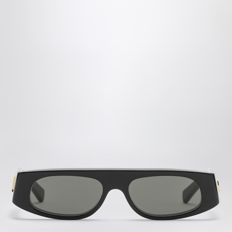 구찌의 검은색 광택 아세테이트 선글라스는 기하학적 모양, 템플에 새겨진 골드톤 메탈 로고, 단색 회색 렌즈가 특징입니다. 이미지