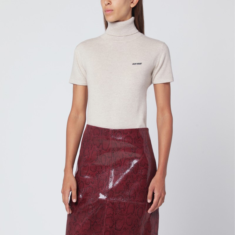 모래색의 미우미우 캐시미어 스웨터는 높은 칼라, 짧은 소매, 가슴 부분에 로고 자수, 몸에 꼭 맞는 실루엣이 특징입니다. 이미지