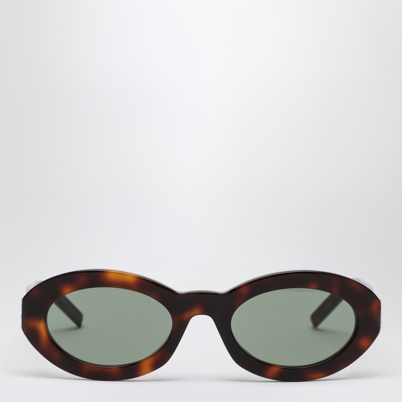 하바나 거북이 껍질 아세테이트 소재의 타원형 프레임, 템플 부분의 골드 메탈 카상드르 디테일, 100% UVA/UVB 차단 기능이 있는 검은색 렌즈가 특징인 생 로랑 선글라스입니다. 이미지