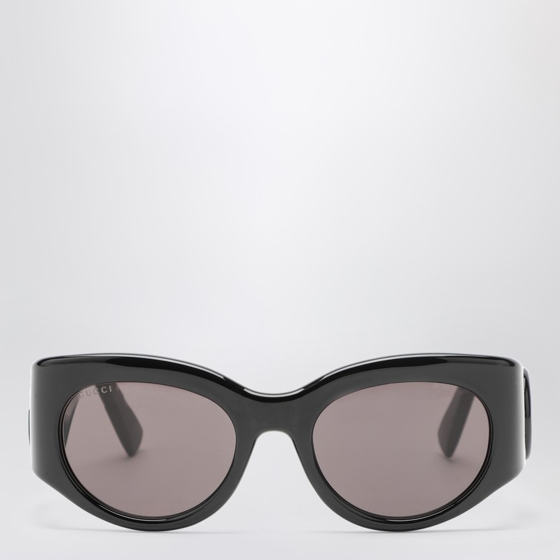 구찌의 검은색 광택 아세테이트 선글라스는 타원형 모양, 톤온톤 더블 G 로고 디테일이 들어간 높은 템플 프레임, 심플한 회색 렌즈가 특징입니다. 이미지