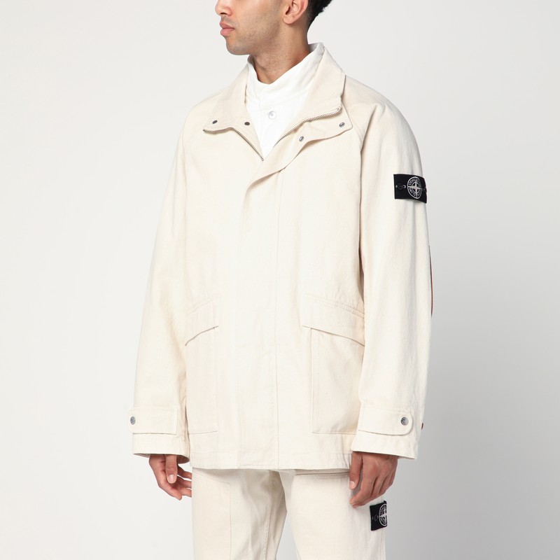 아이보리 코튼 소재의 Stone Island 파카는 지퍼와 단추가 있는 은폐형 전면 잠금 장치, 긴 소매(하나는 Compass 로고 라벨 있음), 두 개의 앞면 플랩 포켓, 조절 가능한 커프스, 고무 로고가 특징입니다. 이미지