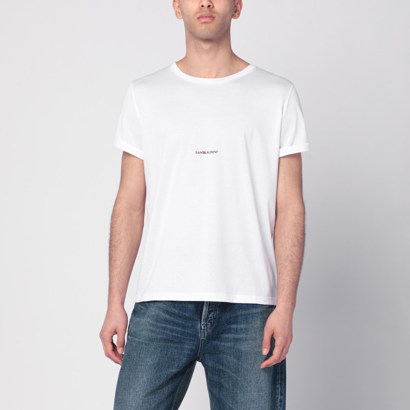 생 로랑의 흰색 크루넥 티셔츠는 짧은 소매, 앞면 로고 프린트, 스트레이트 밑단이 특징입니다. 이미지