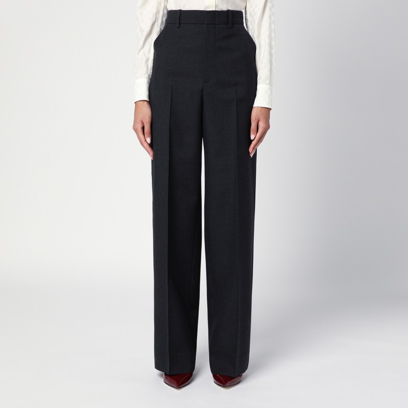 구찌의 다크 그레이 울 루즈핏 팬츠는 톤온톤 레터링 로고 자수가 있는 하이 웨이스트, 앞면 지퍼와 후크 앤 아이 고정 장치, 허리 고리, 두 개의 측면 웰트 포켓, 두 개의 바가 특징입니다. 이미지