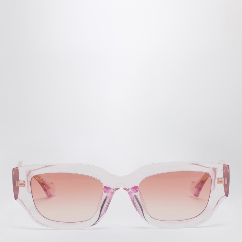 구찌의 핑크/투명 아세테이트 선글라스는 직사각형 모양, 템플에 GG 컷아웃 프린트 디테일이 있는 프레임, 회색 그라데이션 렌즈가 특징입니다. 이미지