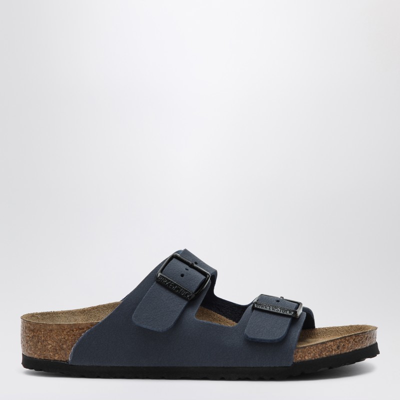 버켄스탁의 네이비 블루 가죽 슬라이드는 둥근 앞부분, 조절 가능한 로고 버클이 달린 스트랩, 해부학적 모양의 코르크와 라텍스 풋베드, EVA 고무 밑창이 특징입니다. 이미지