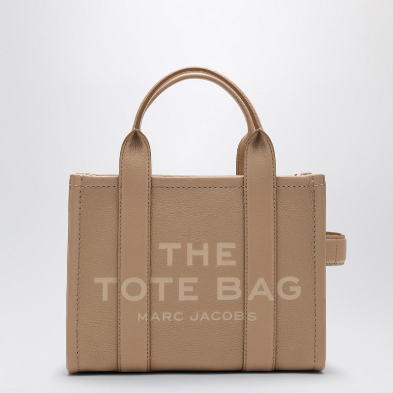 마크 제이콥스(Marc Jacobs)의 카멜 색상 스몰 가죽 토트백입니다. 앞면 로고, 상단 핸들 두 개, 뒷면 로고 삽입물, 상단 지퍼 잠금 장치, 내부 포켓이 특징입니다. 탈부착 가능한 탈착식 숄더 스트랩이 있습니다. 이미지