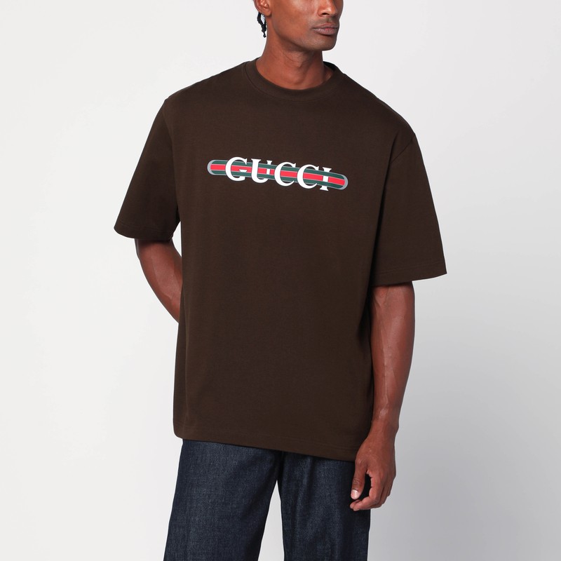 갈색 코튼 구찌 티셔츠, 짧은 소매, 가슴 부분에 대조적인 웹 리본이 있는 로고 문자 프린트, 리브 크루넥이 특징입니다. 이미지