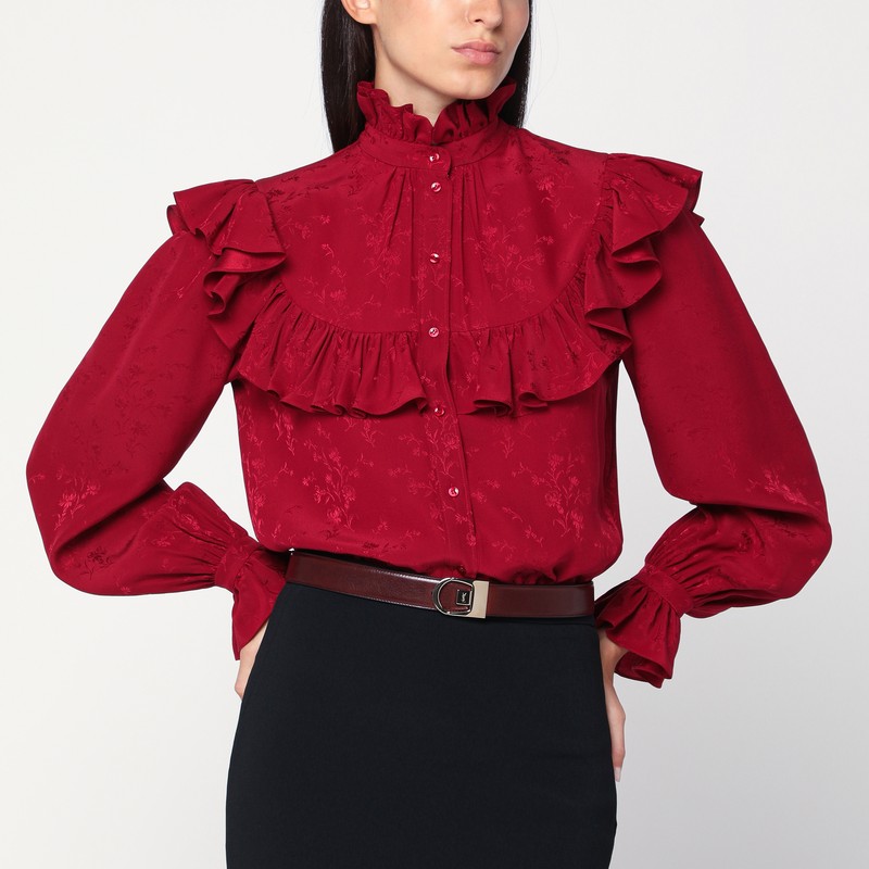 다마스크 꽃무늬가 들어간 생 로랑 레드 실크 셔츠. 앞 단추, 단추로 고정하는 커프스와 주름 장식이 있는 긴 소매, 높은 칼라와 앞면과 뒷면에 주름 장식이 특징입니다. 이미지