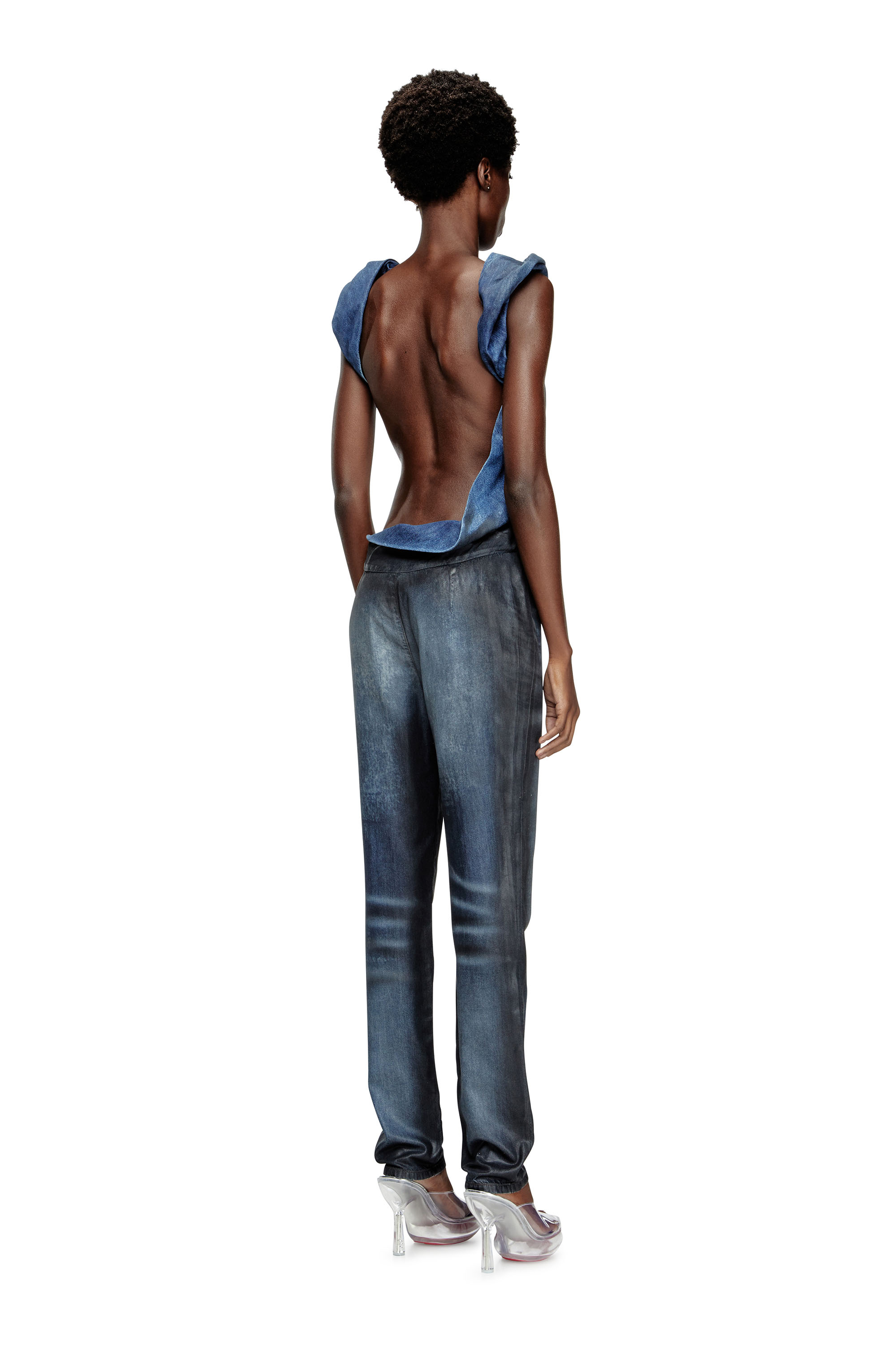 2025년 봄 여름 런웨이 컬렉션의 돋보이는 룩인 이 데님 점프수트는 두 가지 톤의 대리석 워싱 원단을 결합하여 신체의 자연스러운 곡선에 맞게 재단되어 비대칭적인 느낌을 연출합니다. 이미지