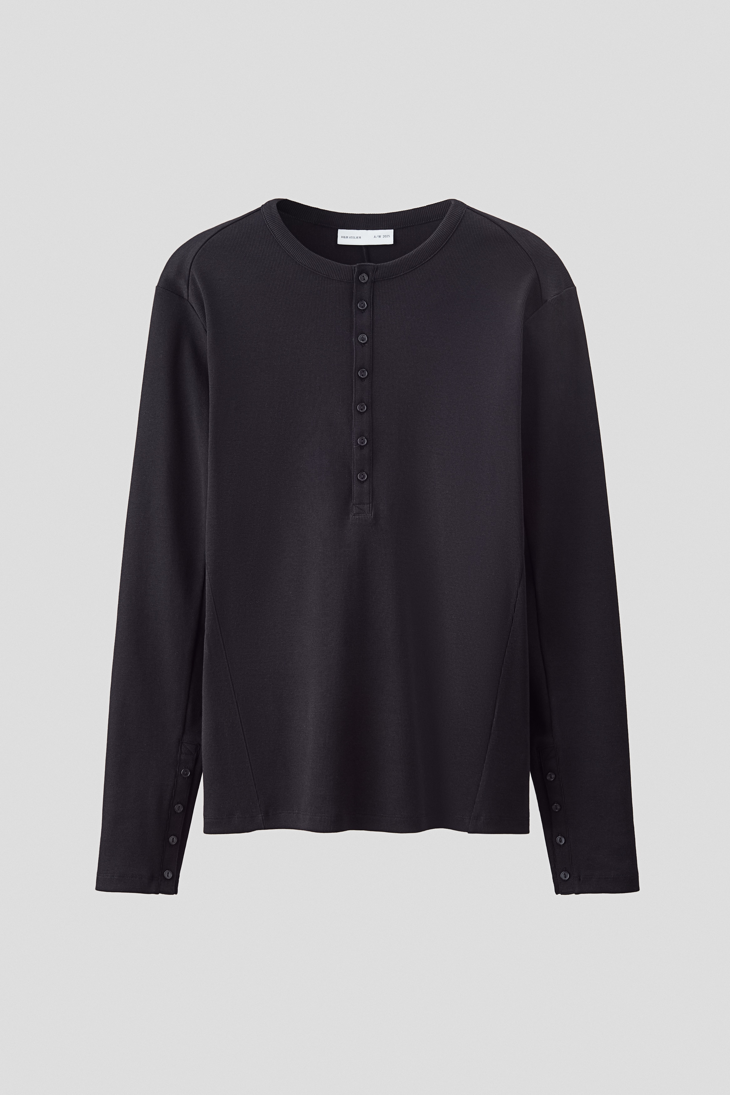 톡톡한 코튼 리브드 저지 소재의 헨리탑. 슬림핏. 리브드 마감된 라운드넥. 상단 버튼 플래킷. 플래킷이 있는 긴소매. 앞뒷면이 비대칭적으로 재단됨. 스트레이트 헴라인. 이미지