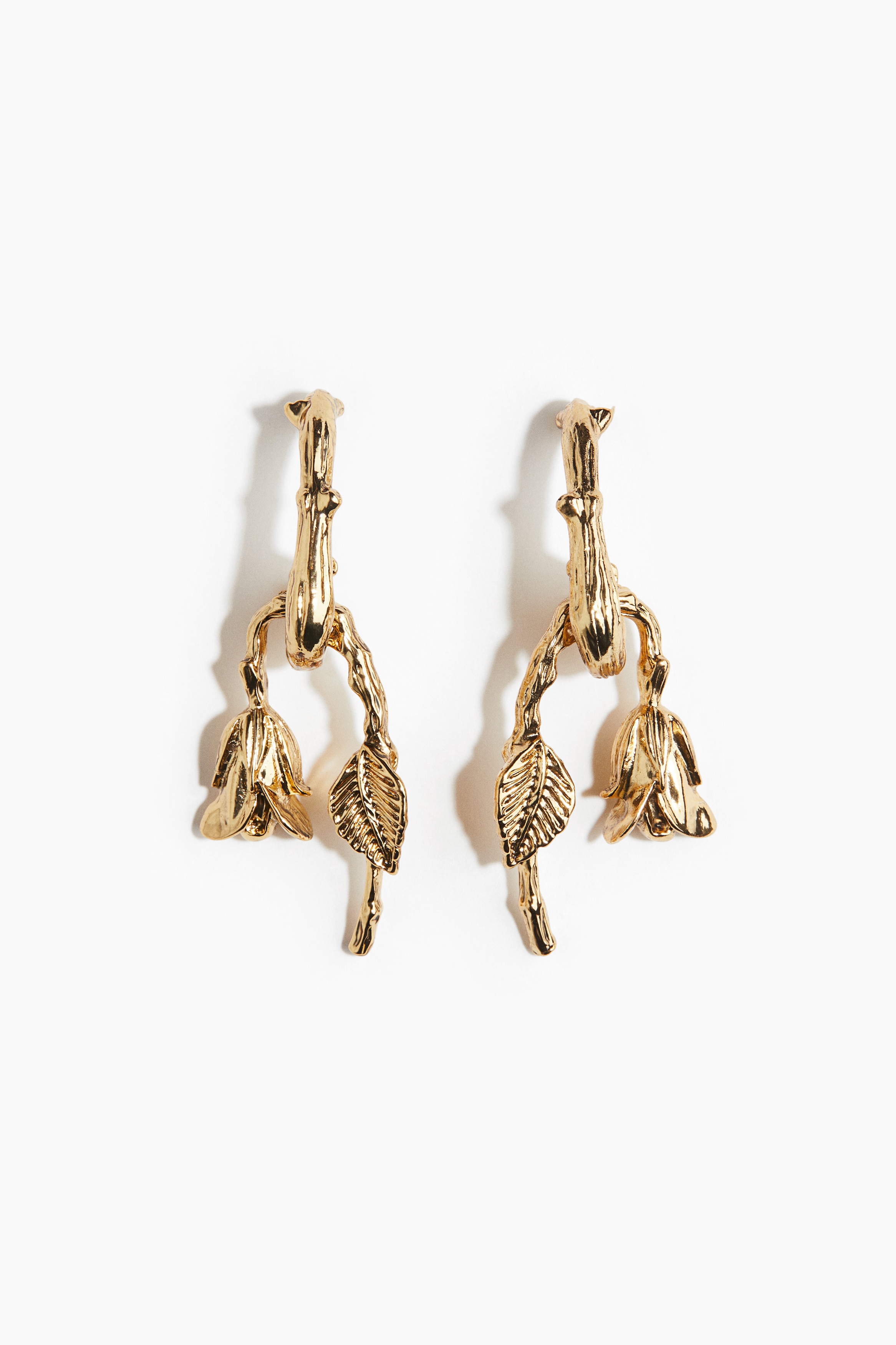 텍스처가 있는 금속 소재의 링 귀걸이. 시들어가는 장미 모양의 펜던트 장식. 이미지