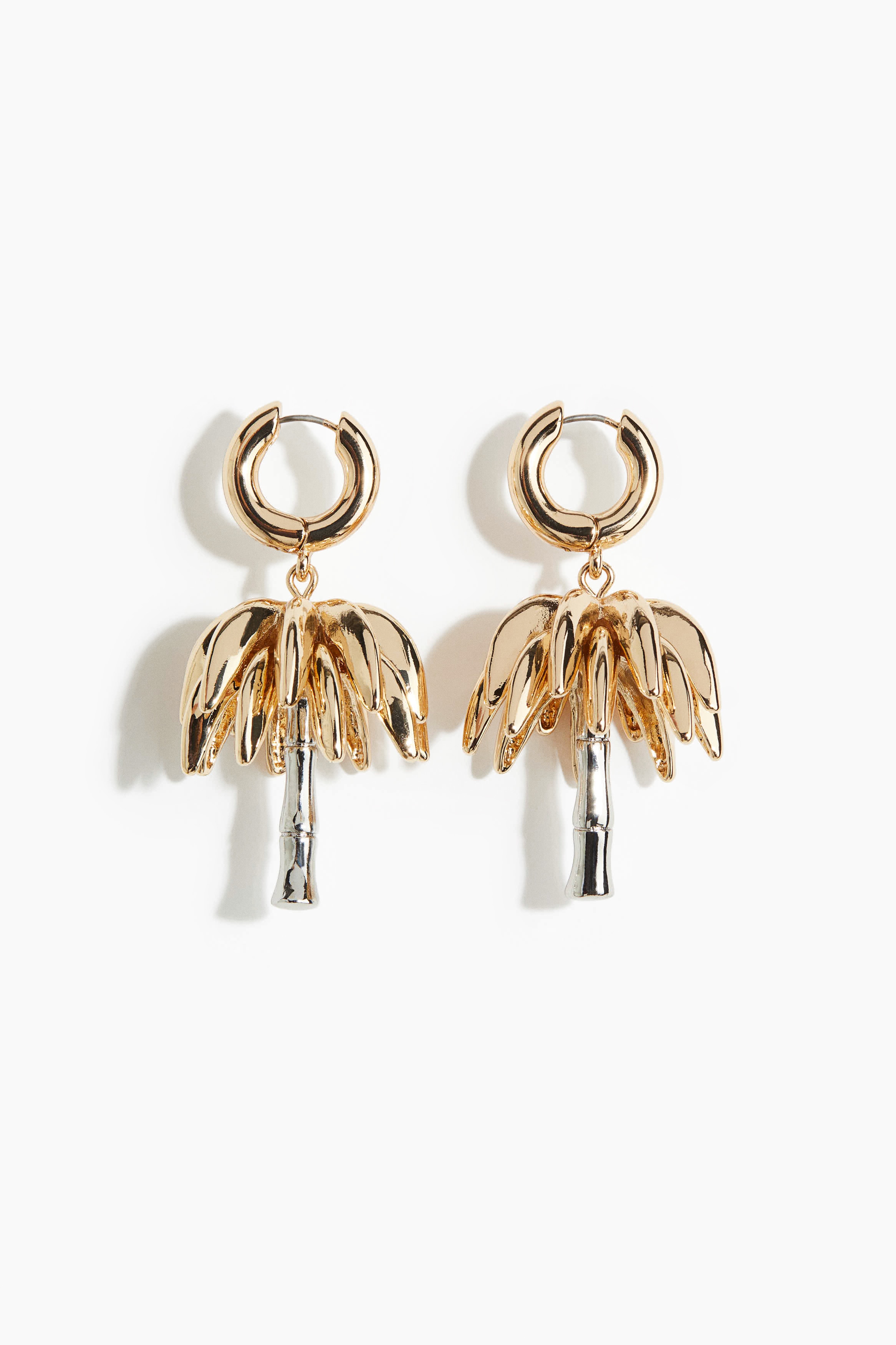 금속 소재의 투톤 링 귀걸이. 반짝이는 야자수 모양 펜던트가 움직일 때마다 부드럽게 흔들리는 디자인. 이미지