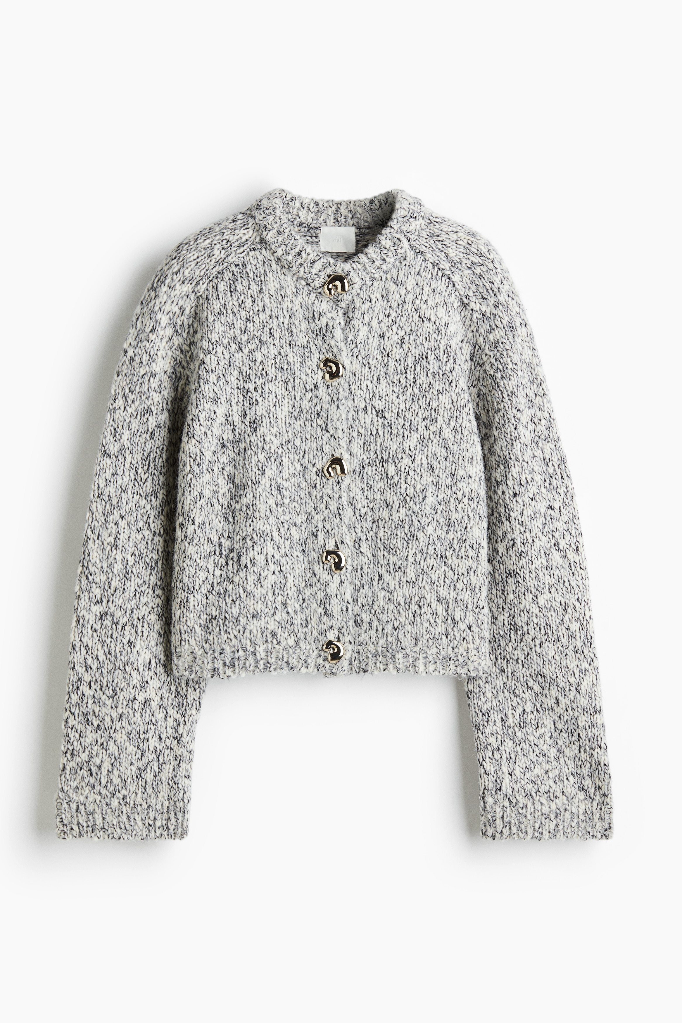 부드러운 니트 소재의 짧은 라운드넥 가디건. 추상적인 디자인이 들어간 앞면 금속 버튼. 새들 스타일의 긴소매. 리브드 옷단. 이미지