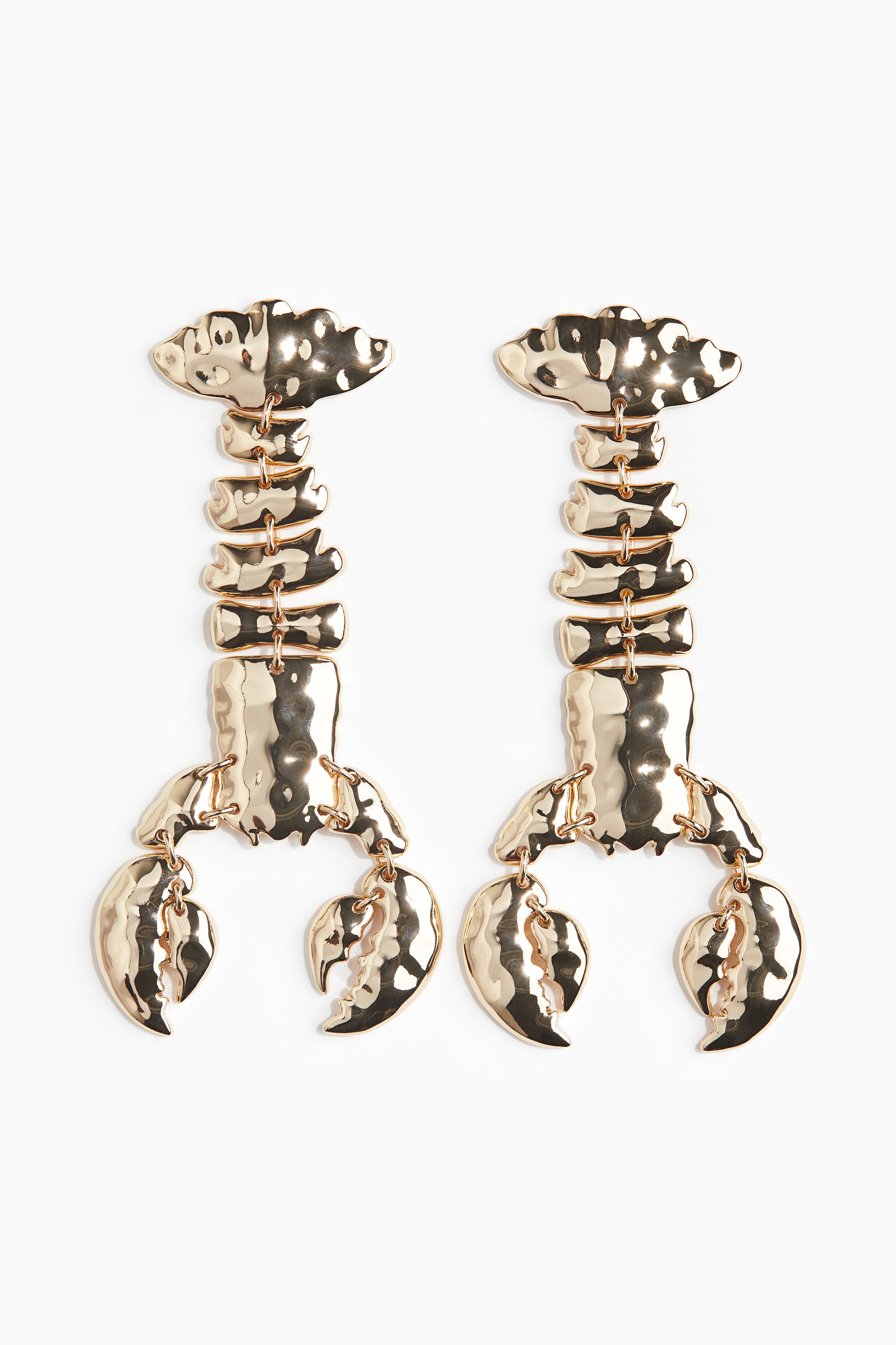 텍스처가 있는 금속 소재의 가재 모양 귀걸이. 여러 개의 피스가 연결되어 매혹적으로 움직이는 디자인. 이미지