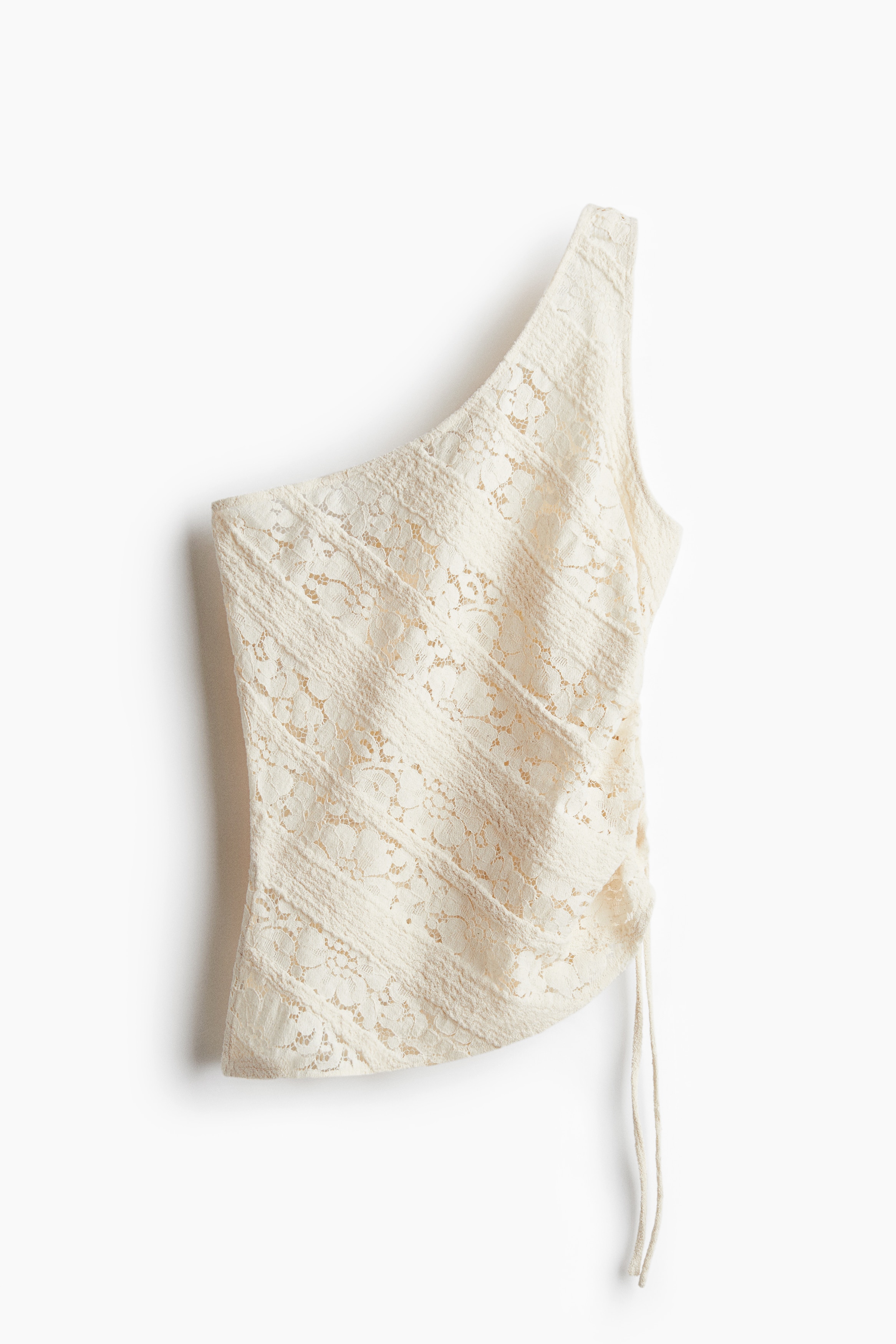 텍스처가 있는 부드러운 저지 소재의 피트되는 탑. 여러 개의 레이스 패널로 마감됨. 한쪽 어깨에만 와이드한 스트랩이 있음. 한쪽 옆면에 드로스트링으로 가볍게 드레이핑 효과를 준 디자인. 한쪽 옆면에 긴 트임이 있는 언발란스 헴라인. 이미지