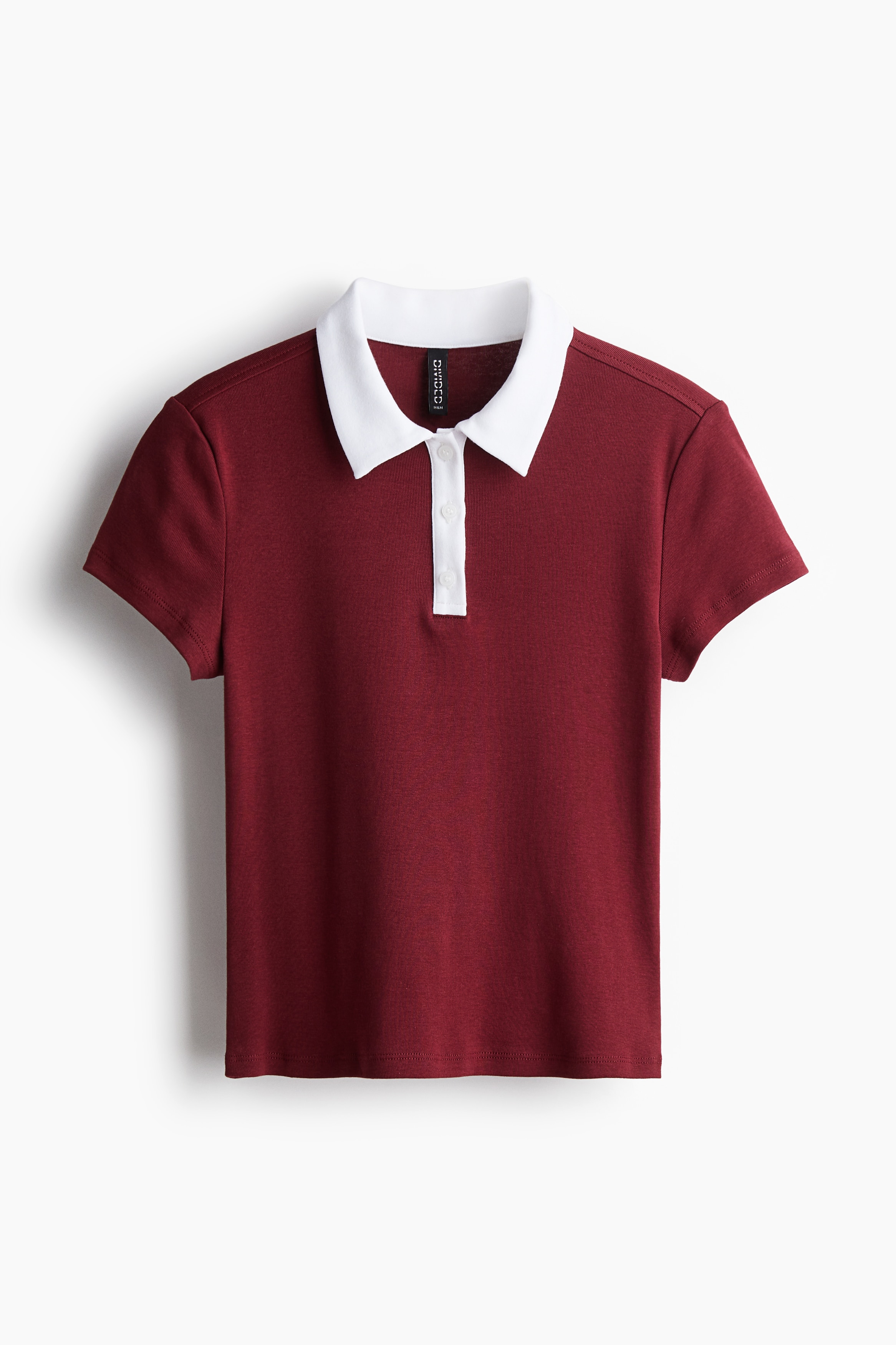 부드러운 코튼 저지 소재의 피트되는 반소매 폴로셔츠. 크롭트 스타일. 칼라와 상단 버튼단이 있음. 이미지