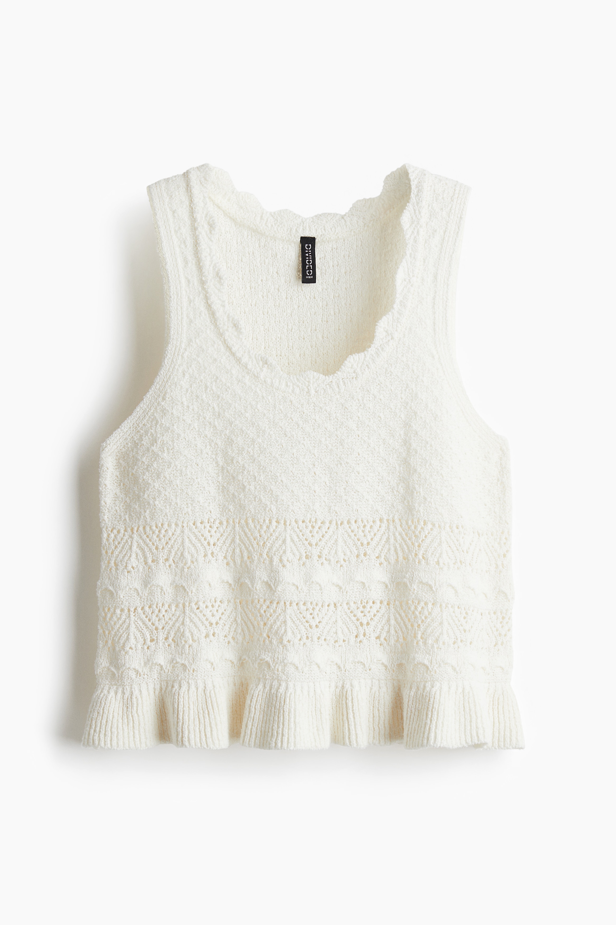 부드러운 크로셰 느낌의 짧은 슬리브리스 니트 탑. 스캘럽트 라인으로 트리밍된 깊게 파인 라운드넥. 리브드 프릴 마감의 아랫단. 이미지