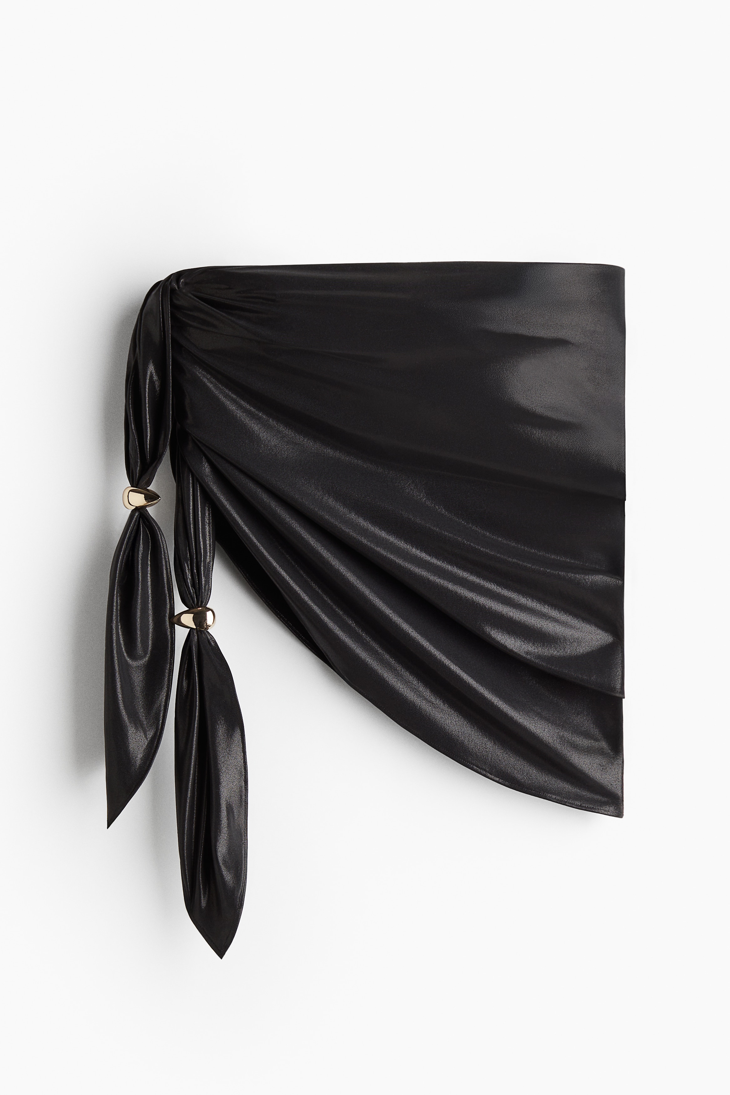 Studio Collection. 광택성 코팅으로 마감된 스트레치 저지 소재의 짧은 사롱. 한쪽 옆면의 긴 끈으로 비대칭 드레이핑 효과를 준 디자인. 끈에 우아함을 더해주는 물방울 모양의 금속 디테일이 있음. 이미지