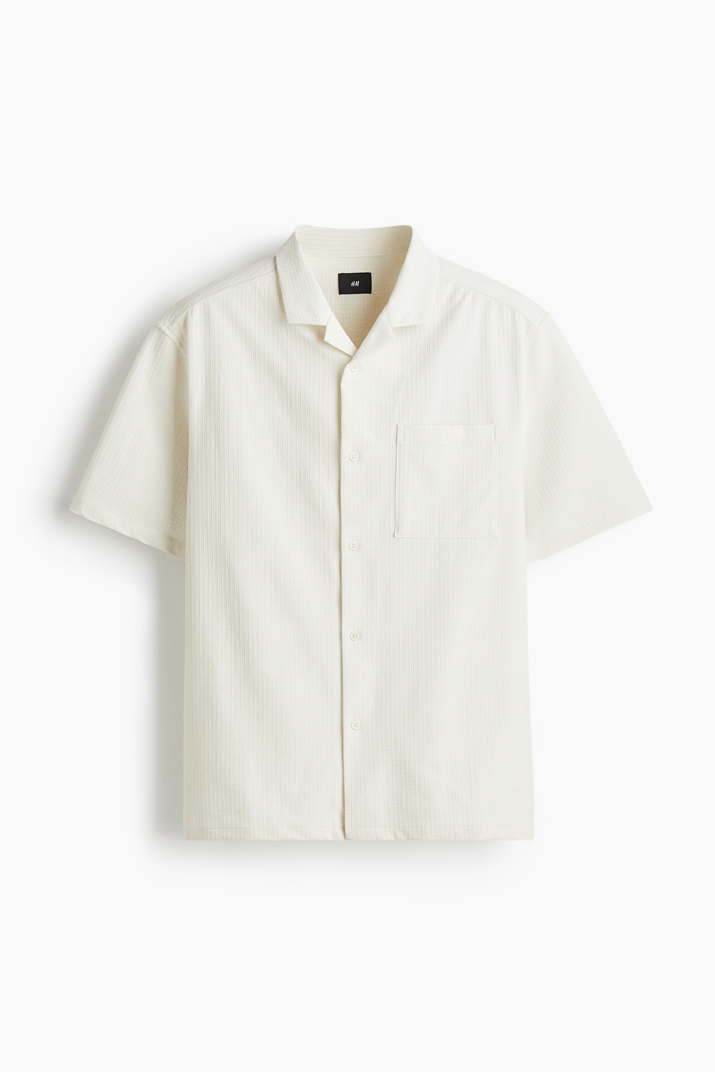 텍스처 소재의 반소매 셔츠. 캠프 칼라. 버튼단이 없는 프렌치 프런트 스타일. 뒷면 요크. 양쪽 옆면에 트임이 있는 스트레이트 헴라인. 넉넉하지만 오버사이즈보다는 약간 피트되는 루즈핏 실루엣. 이미지