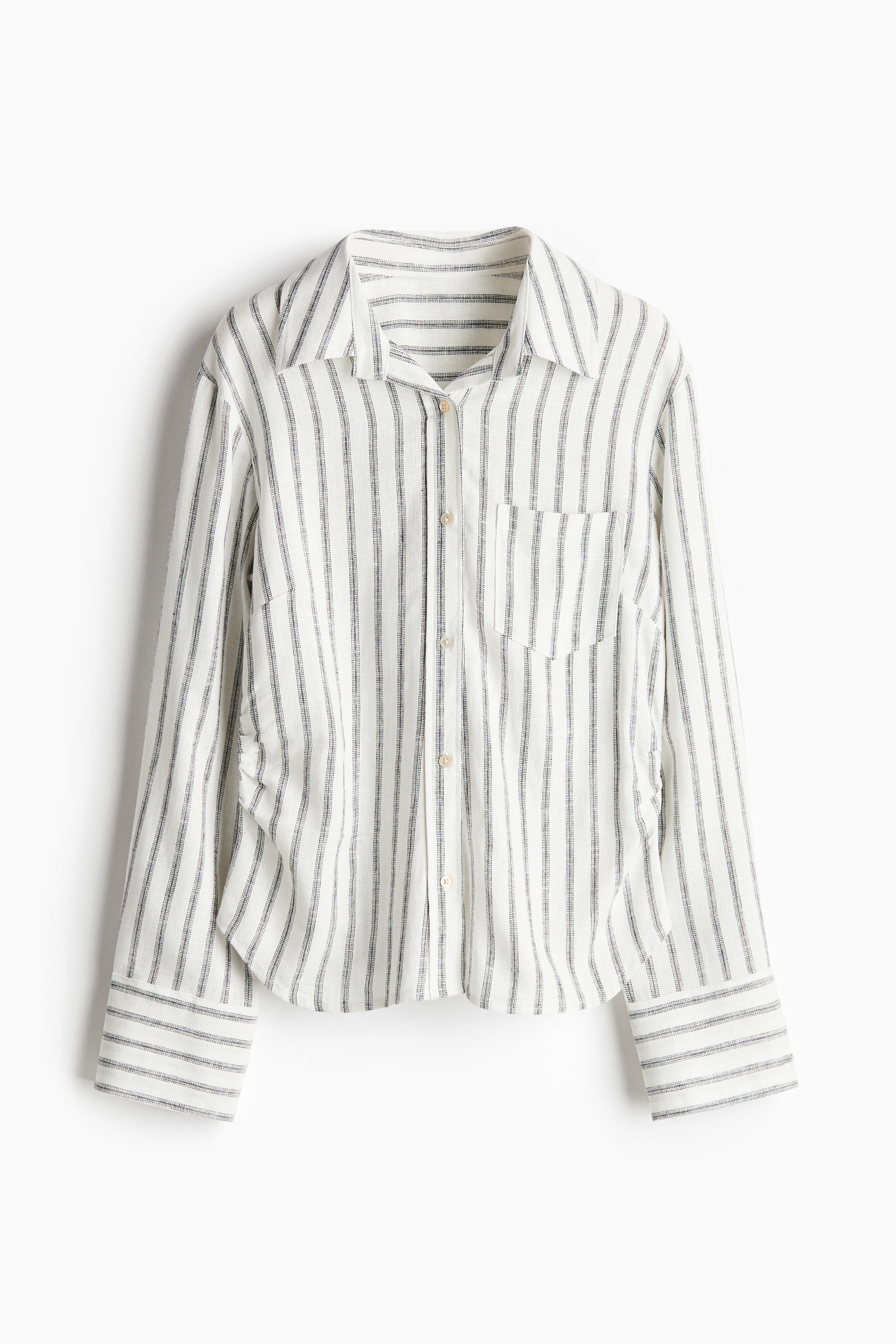 가벼운 리넨, 비스코스 혼방 소재의 피트되는 셔츠. 칼라와 앞면 버튼, 뒷면 요크 디테일이 있음. 가슴 패치포켓. 긴소매. 소맷단 버튼. 옆면에 주름을 잡아 가볍게 드레이핑 효과를 준 디자인. 이미지