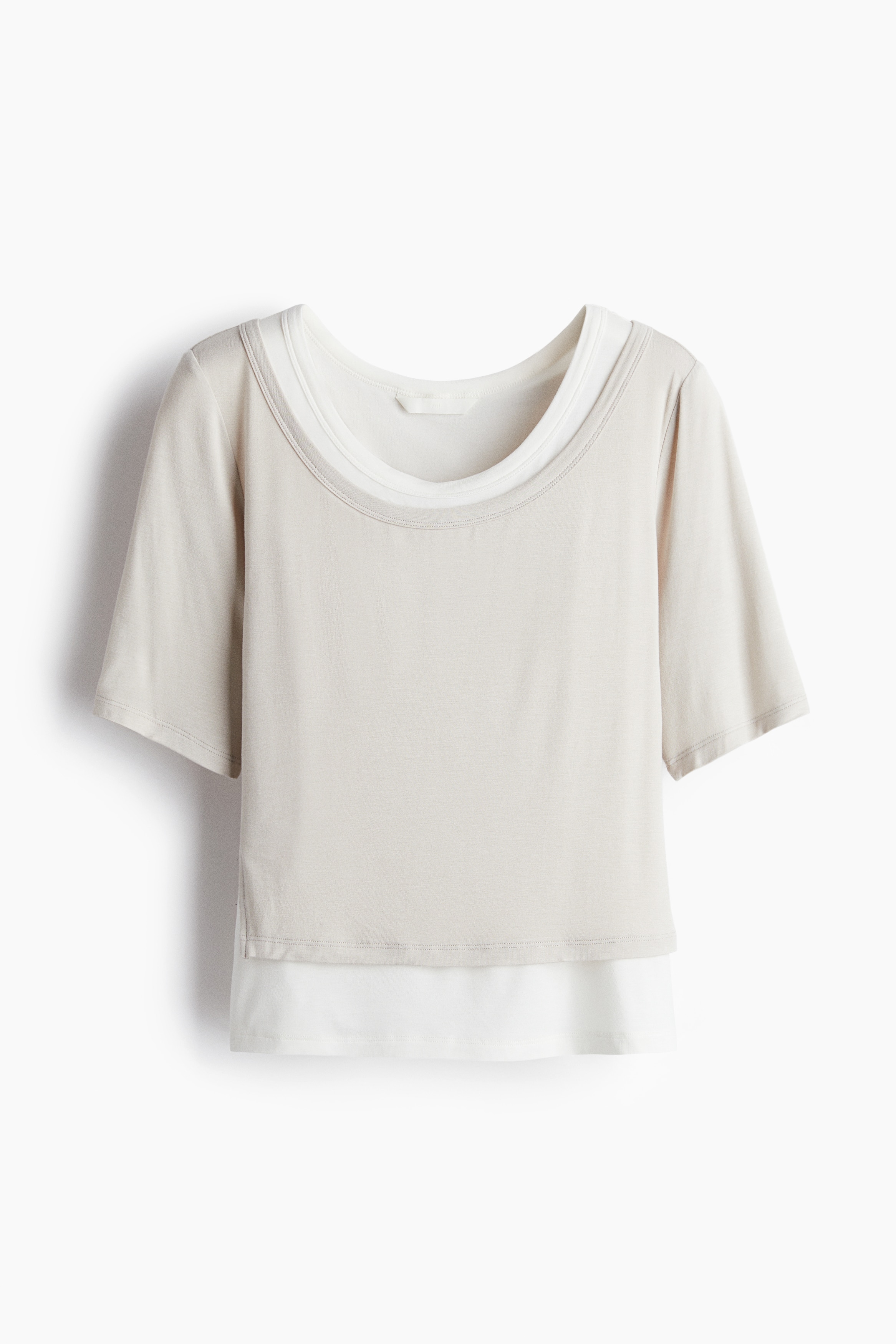 부드러운 저지 소재의 피트되는 탑. 스쿱넥. 반소매. 한쪽 옆면에 트임이 있는 언발란스 실루엣. 이너 슬리브리스 탑이 네크라인과 헴라인 밖으로 살짝 드러나는 디자인. 이미지