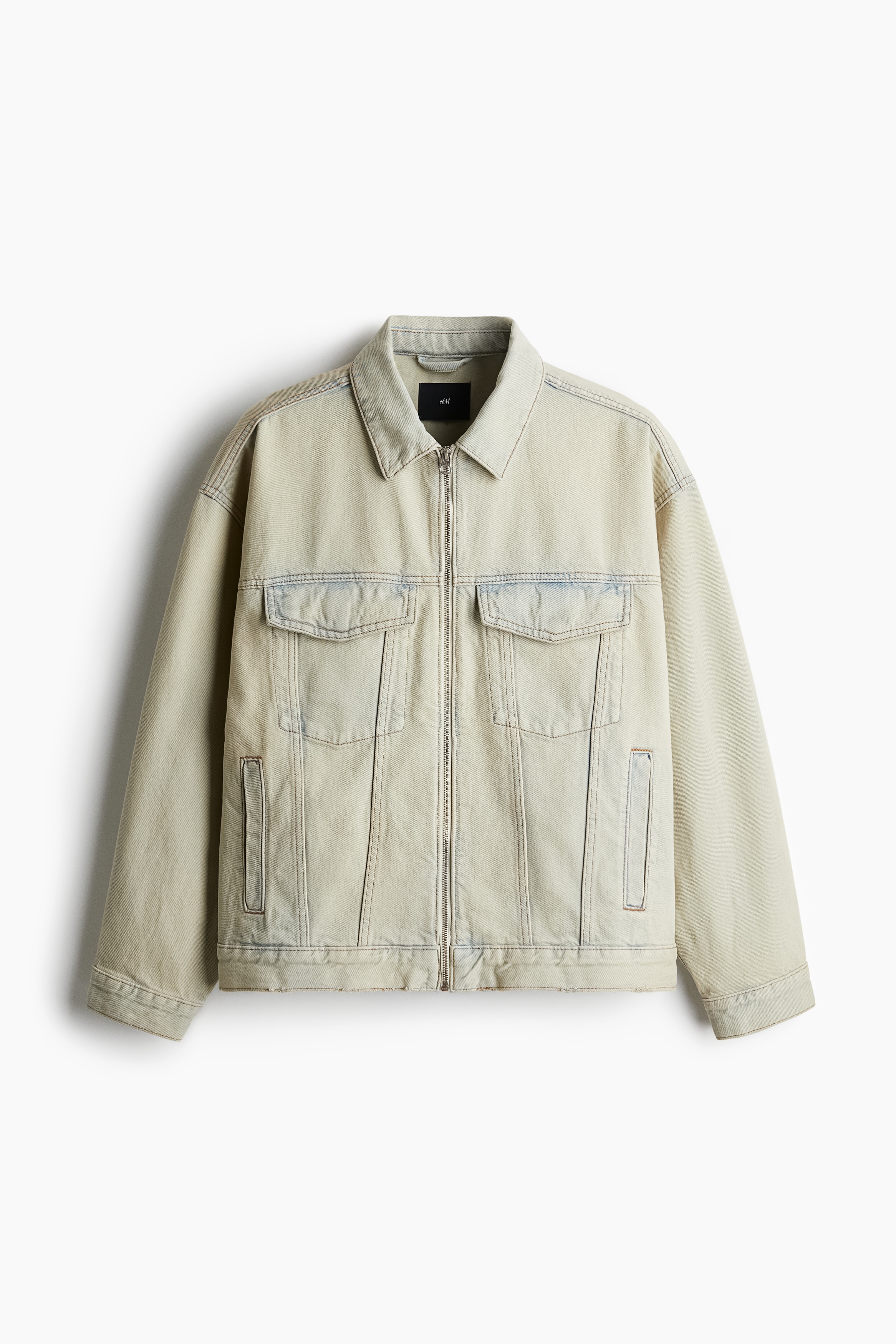 탄탄한 코튼 데님 소재의 재킷. 칼라와 앞면 지퍼가 있음. 뒷면 요크 디테일. 옆면 포켓. 히든 스냅버튼으로 여닫는 가슴 플랩포켓. 긴소매. 소맷단 버튼. 옆면 탭과 버튼으로 핏 조절. 스트레이트 헴라인. 넉넉하지만 오버사이즈보다는 약간 피트되는 루즈핏 실루엣. 이미지