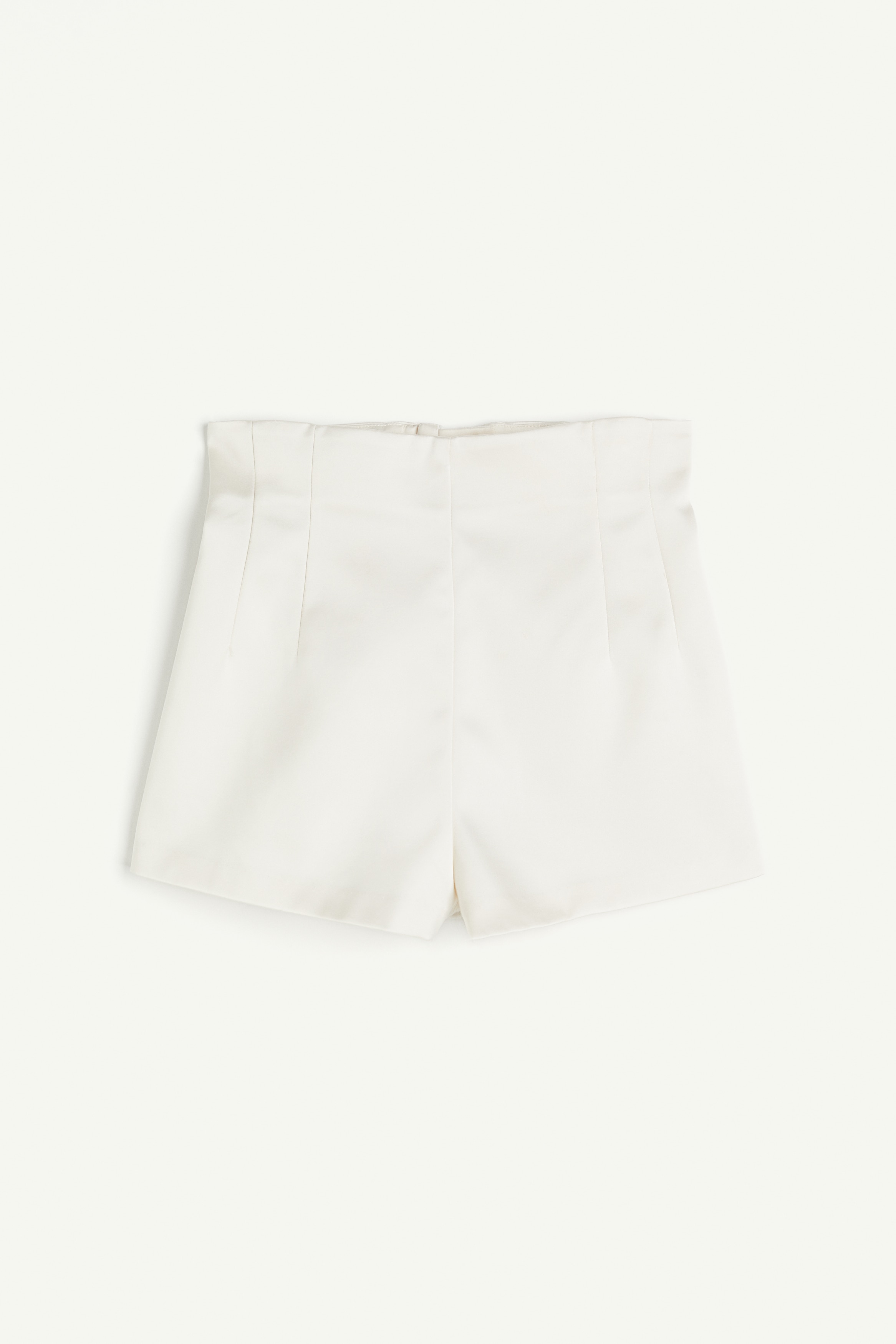 광택성 트윌 소재의 짧은 반바지. 하이웨이스트. 허리 부분에 다트를 잡아 라인을 살린 디자인. 뒷면 히든 지퍼와 버튼 클로저. 옆면 히든 포켓. 이미지1