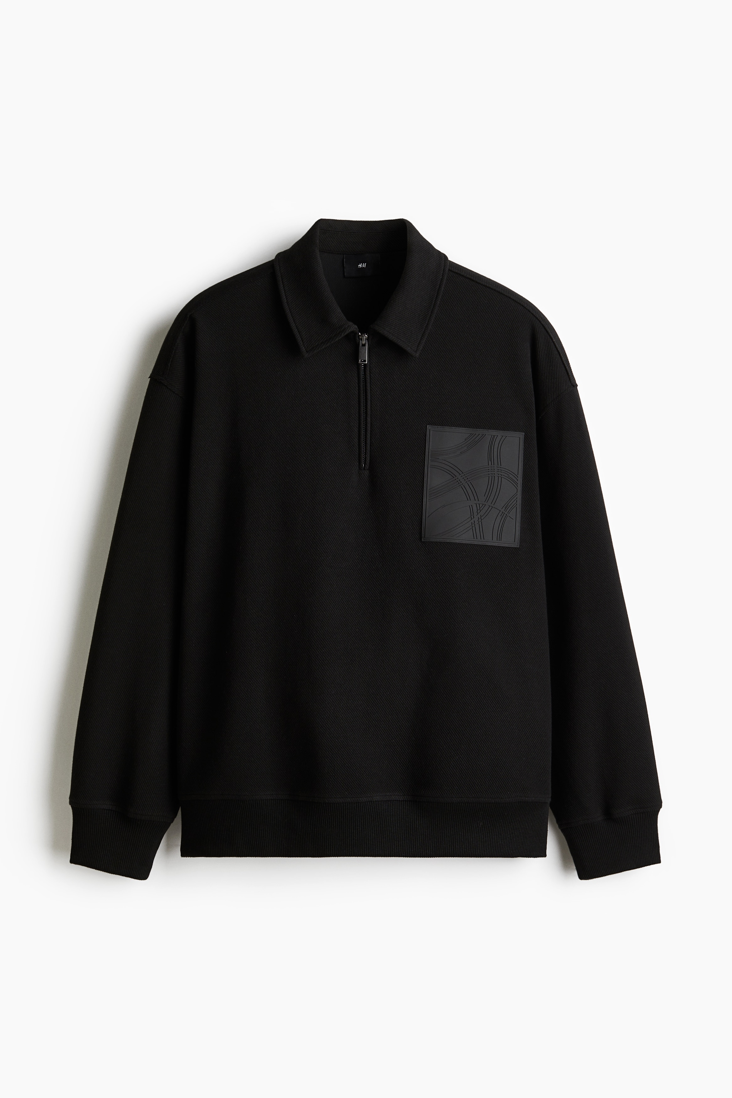 칼라가 있는 부드러운 트윌 소재의 긴소매 폴로셔츠. 상단 지퍼. 드롭 숄더. 와이드한 리브드 마감의 소맷단과 아랫단. 가슴 부분의 실리콘 패치 장식. 넉넉하지만 오버사이즈보다는 약간 피트되는 루즈핏 실루엣. 이미지