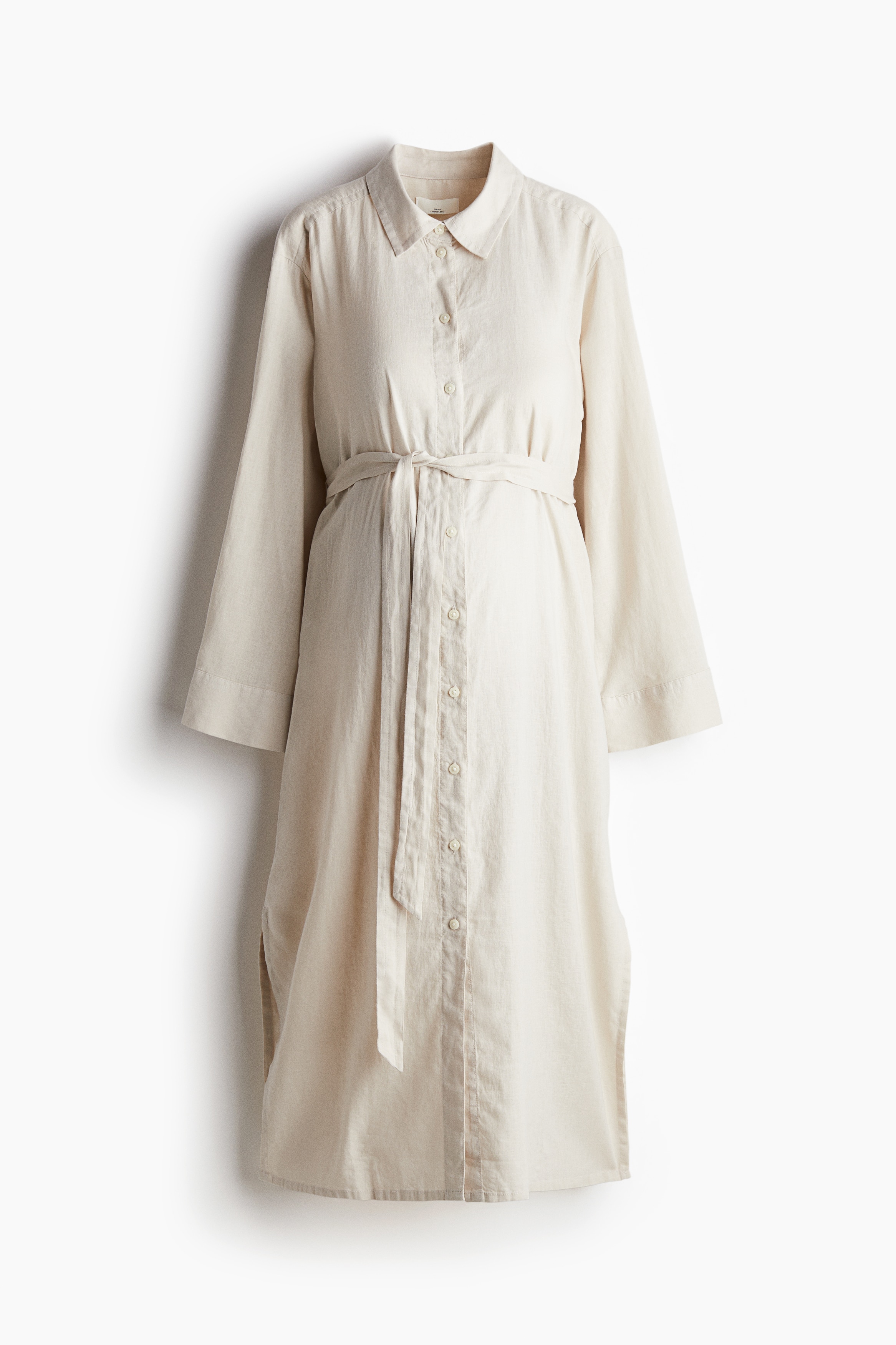 칼라가 있는 가벼운 리넨 혼방 비스코스 소재의 미디 원피스. 버튼업 스타일. 루즈핏. 2겹으로 마감된 뒷면 요크. 플래킷이 있는 긴소매, 소맷단 버튼. 가슴 아래에 탈부착식 끈 벨트를 두른 디자인. 옆면 하단에 트임이 있는 스트레이트 헴라인. 안감 생략. 이미지