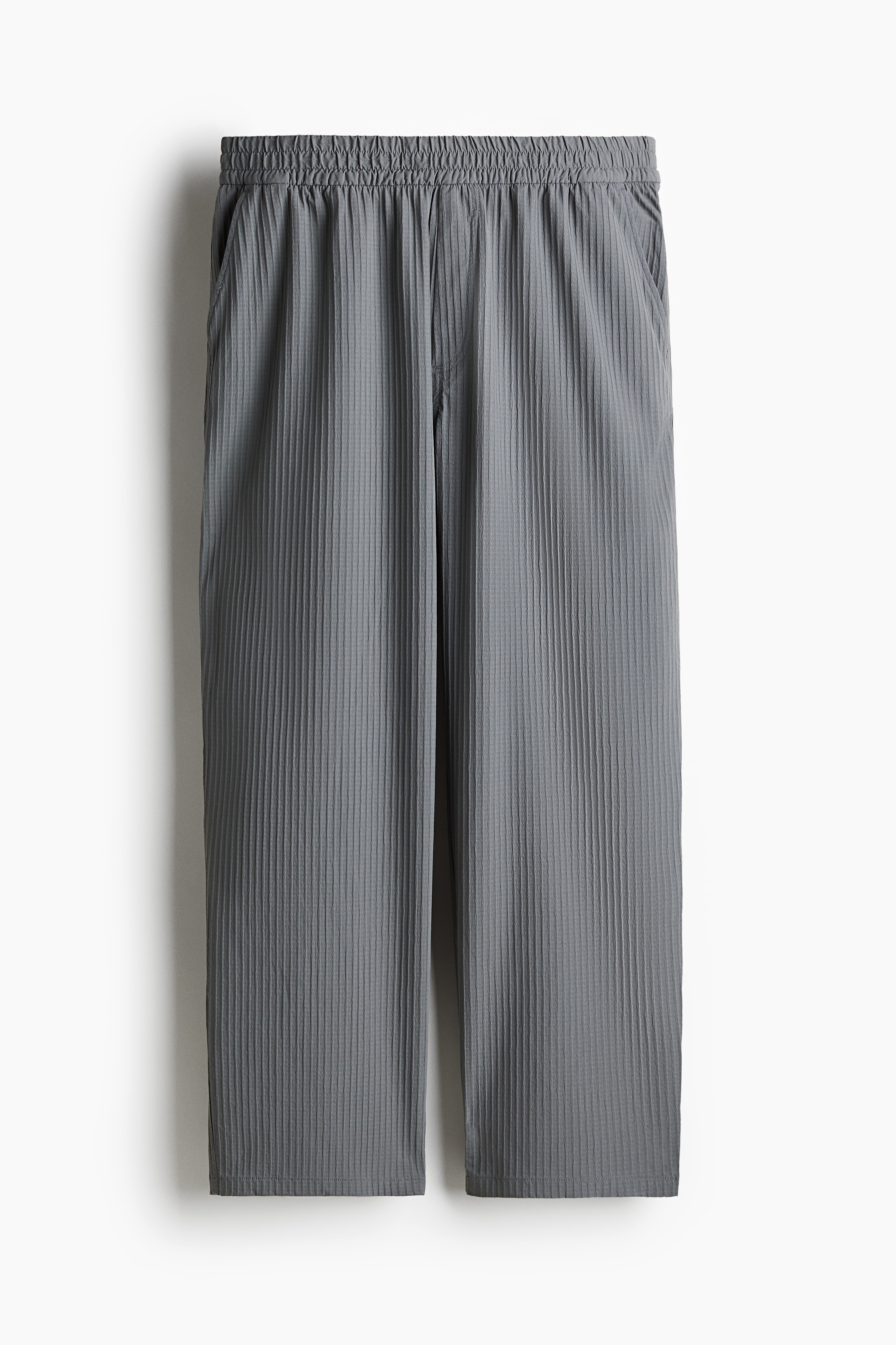 와플 텍스처가 있는 나일론 소재의 팬츠. 스모킹 주름이 잡힌 신축성 허릿단에 드로스트링이 내장됨. 페이크 플라이. 사선 방향의 옆면 포켓. 뒷면 페이크 포켓. 넉넉하지만 오버사이즈보다는 약간 피트되는 루즈핏 실루엣. 이미지