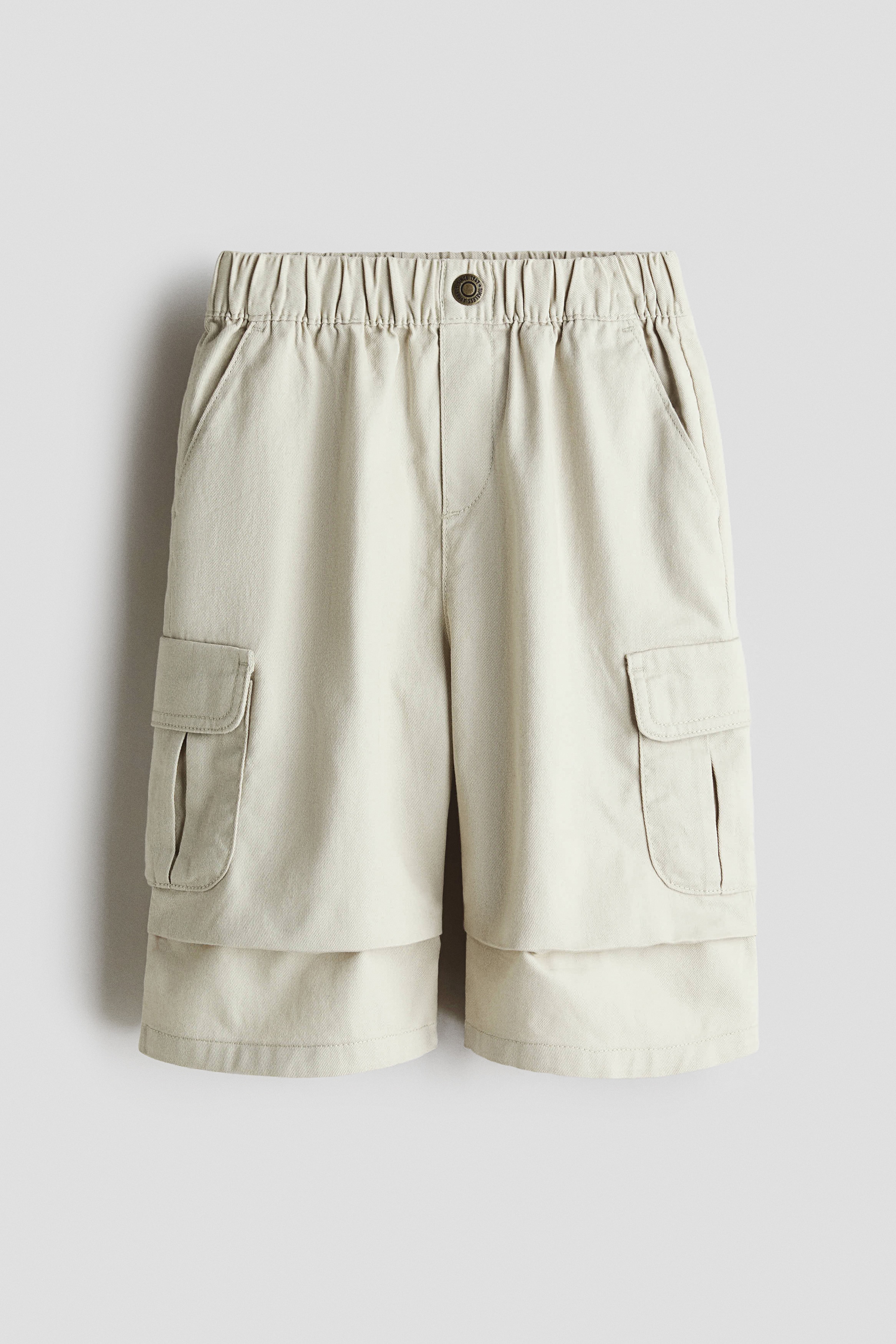 부드러운 코튼 트윌 소재의 7부 팬츠. 페이크 플라이와 버튼 장식이 있는 신축성 허릿단. 플리츠가 잡힌 와이드 레그. 다리 플랩포켓, 뒷면 포켓. 이미지