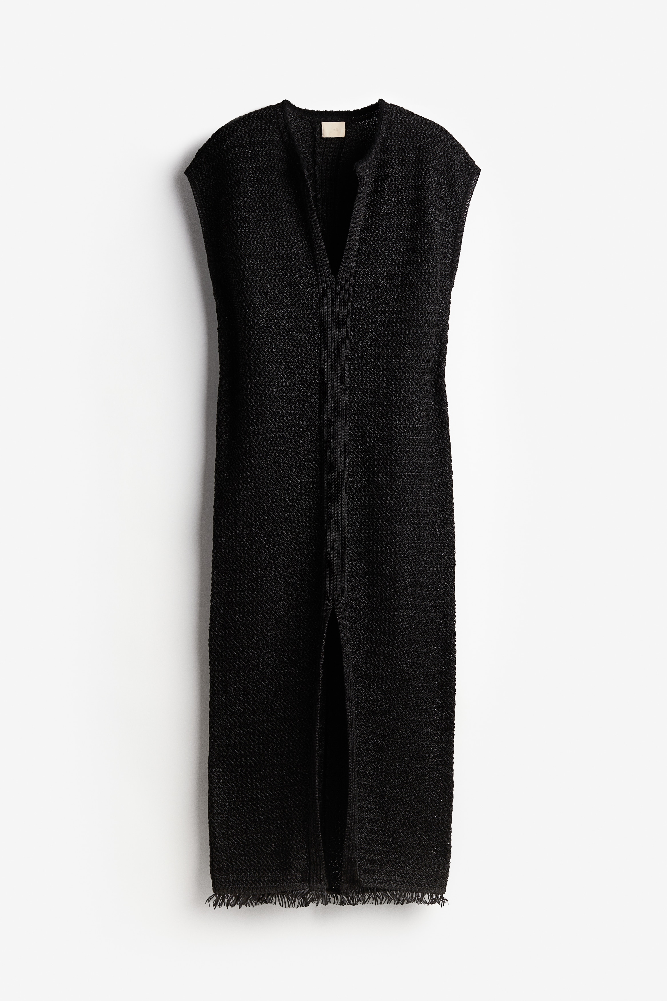 라피아 느낌을 주는 니트 소재의 롱 카프탄 원피스. 슬리브리스. 깊게 파인 V넥. 앞면 하단에 긴 트임이 있음. 루즈핏. 드롭 숄더. 올이 폴린 듯한 암홀과 헴라인. 안감 생략. 이미지