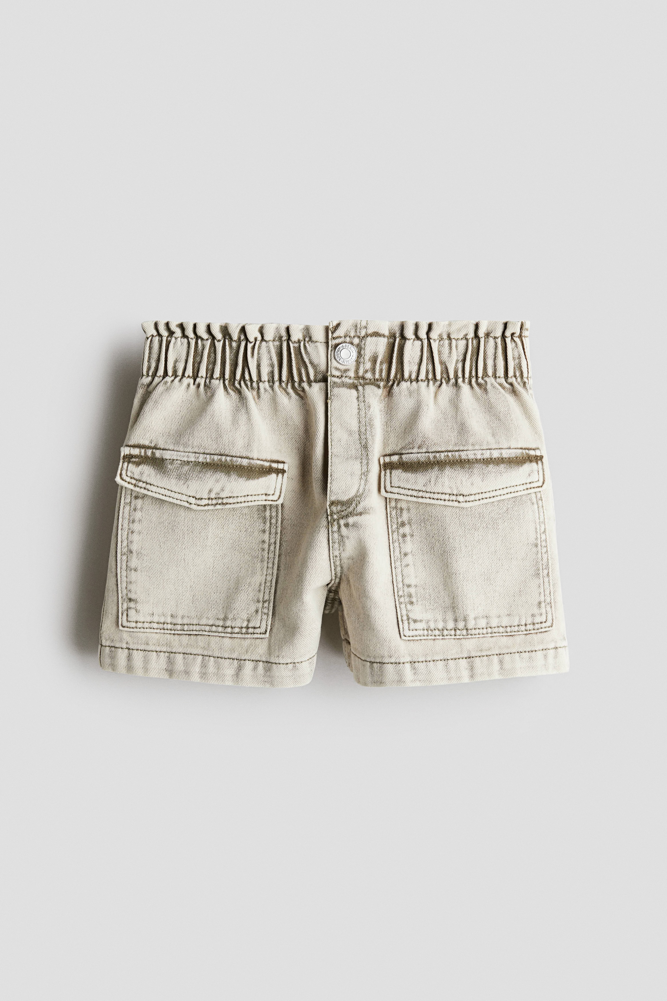 워시드 코튼 데님 소재의 루즈핏 반바지. 페이퍼백 스타일의 신축성 허릿단. 스냅버튼이 있는 페이크 플라이. 사선 방향의 앞면 포켓. 뒷면 포켓. 이미지