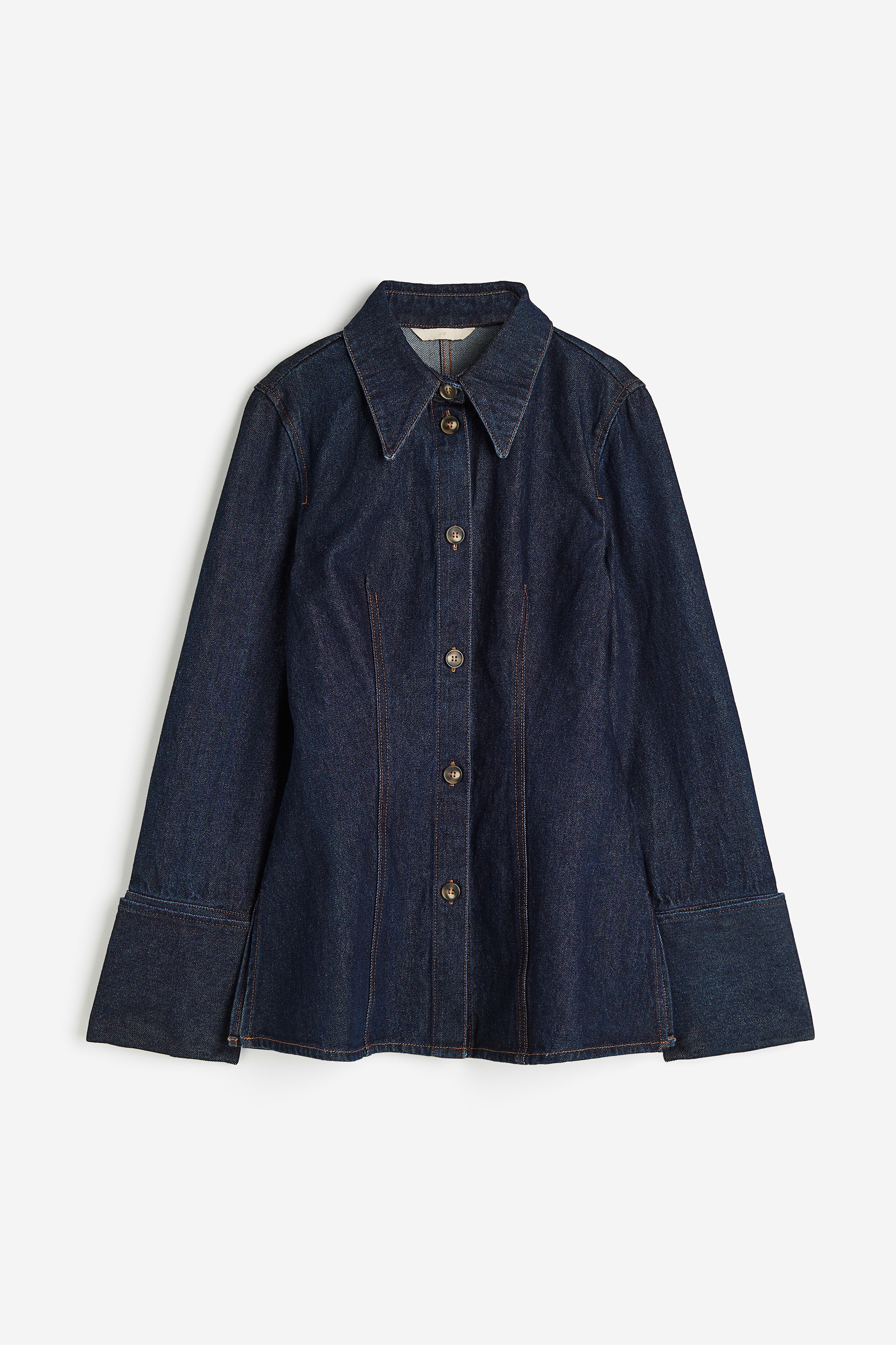 톡톡한 코튼 데님 소재의 피트되는 셔츠. 포인티드 칼라. 앞면 버튼 클로저. 앞뒷면에 다트를 잡아 실루엣을 살린 디자인. 긴소매. 접어 올린 소맷단에 트임과 버튼 장식이 있음. 양쪽 옆면에 트임이 있는 스트레이트 헴라인. 이미지