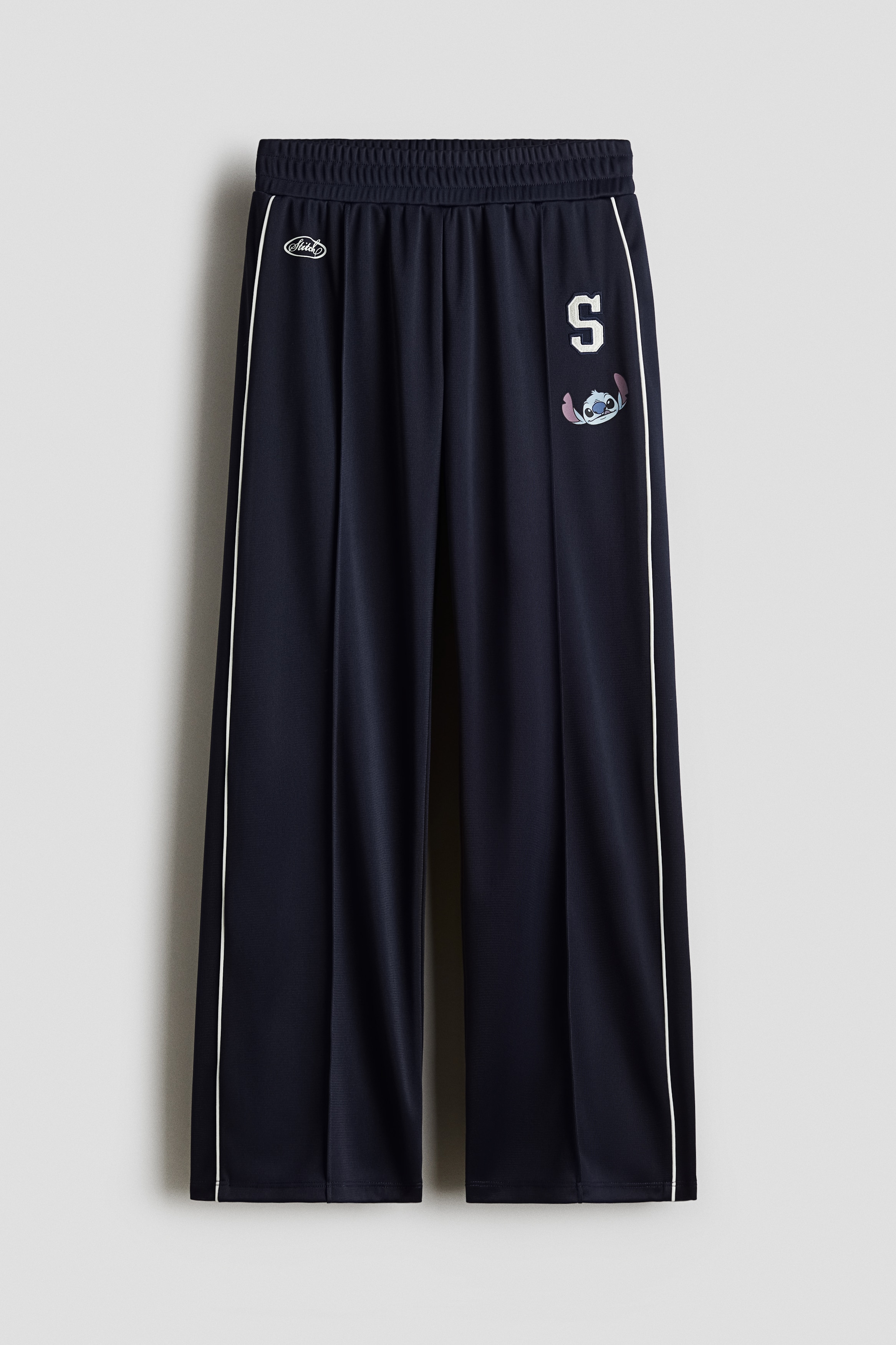 장식이 있는 톡톡한 저지 소재의 트랙 팬츠. 부드럽게 기모처리된 내부. 신축성 허릿단. 앞면에 크리스가 박음질된 와이드 레그. 이미지