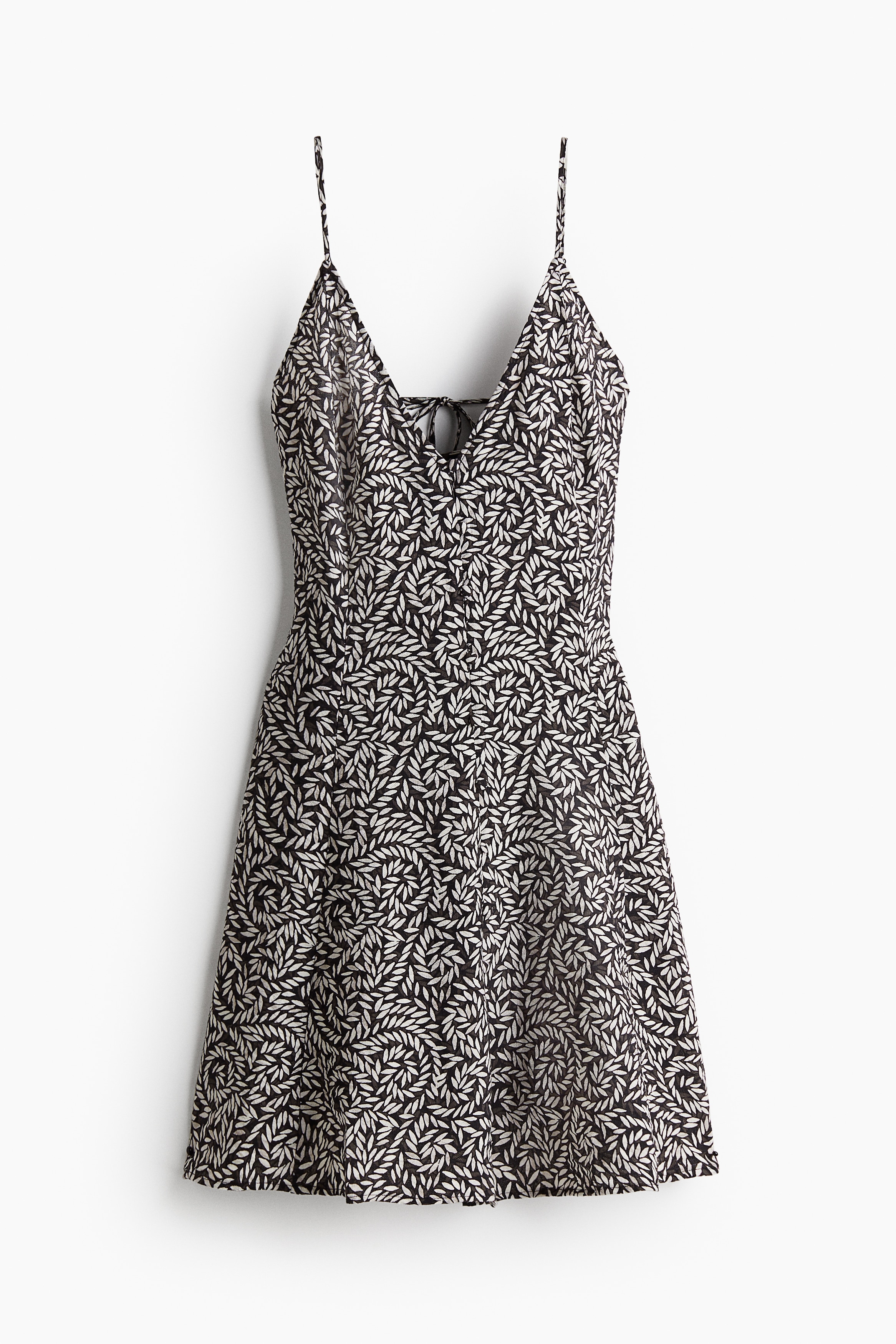 가벼운 우븐 소재의 A라인 미니 원피스. 깊게 파인 V넥. 앞면 커버드 버튼. 길이 조절 가능한 가느다란 어깨 스트랩. 뒷면에서 가로 방향의 끈을 묶는 스타일. 안감 생략. 이미지