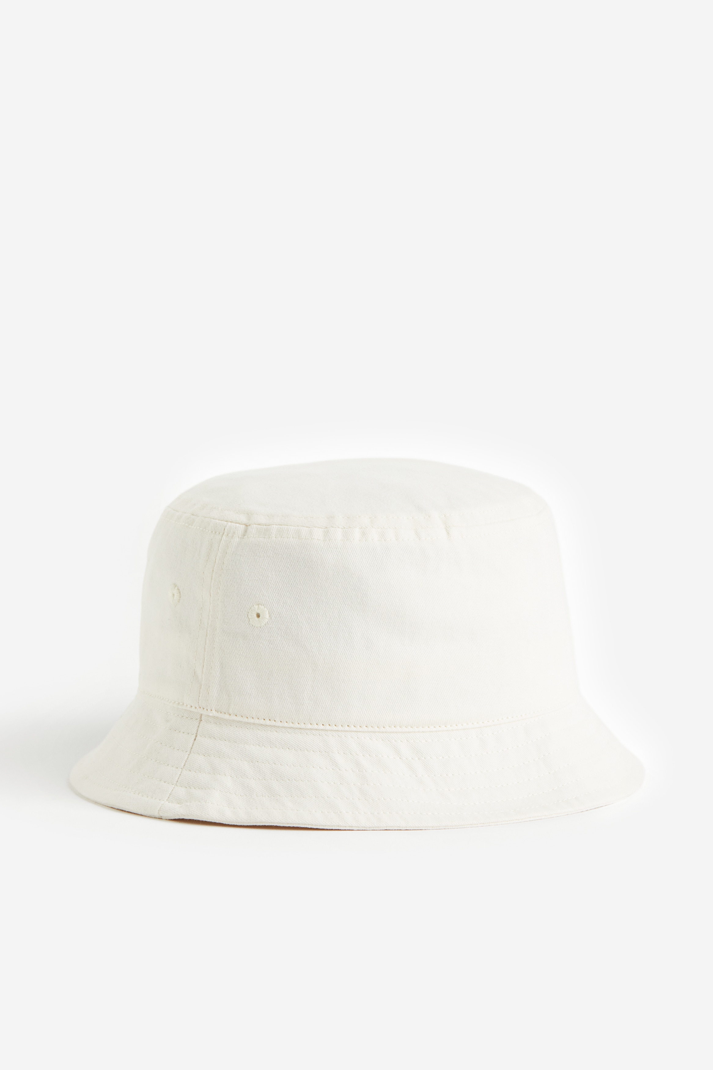 코튼 트윌 소재의 버킷햇. 자수 아일릿. 챙이 비스듬한 디자인. 코튼 스웨트밴드 내장. 이미지