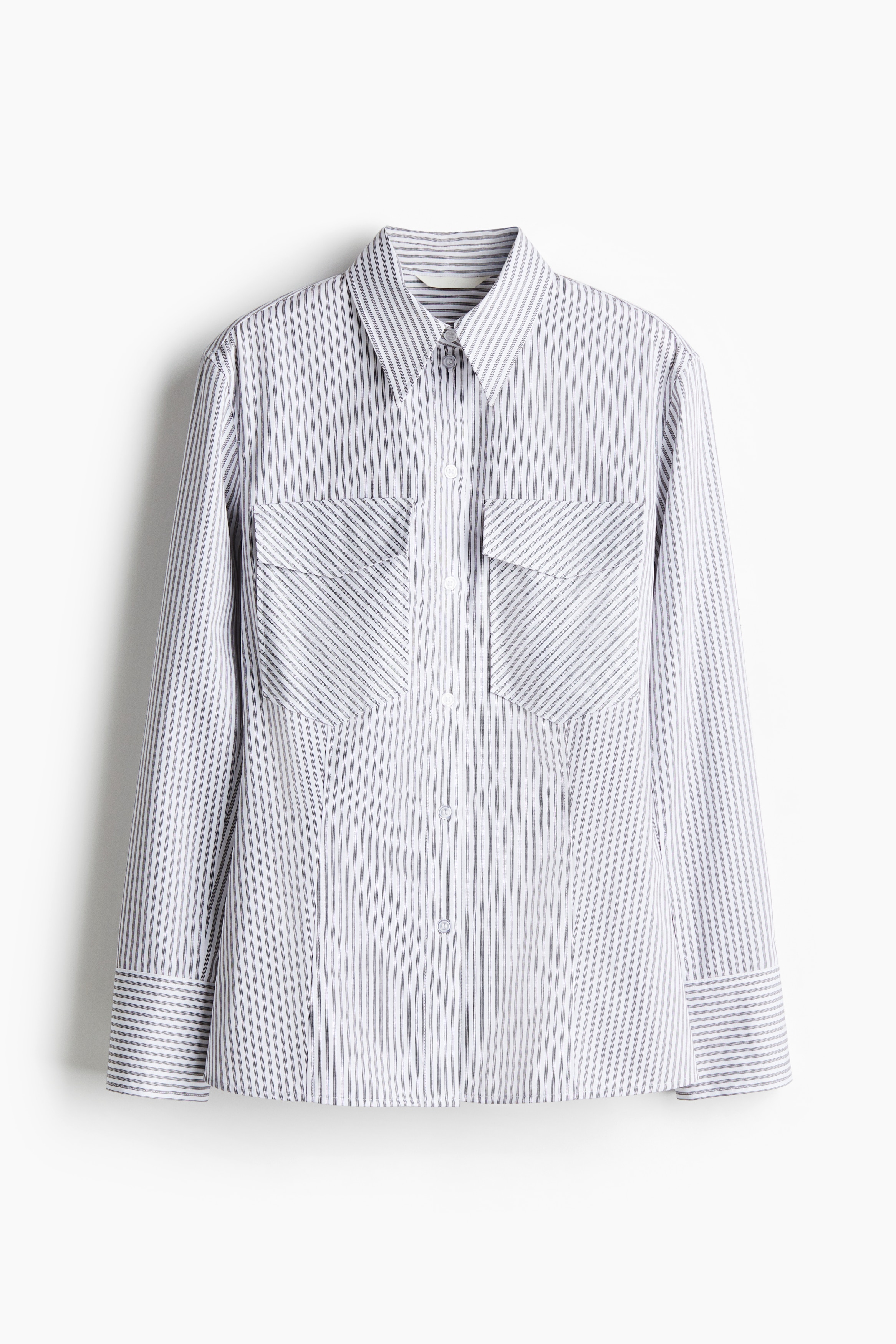 빳빳한 코튼 포플린 소재의 피트되는 롱 셔츠. 포인티드 칼라. 버튼업 스타일. 플랩이 있는 가슴 패치포켓. 뒷면 요크. 긴소매. 소맷단 버튼. 입체감을 주는 앞뒷면 솔기로 실루엣을 살린 디자인. 이미지