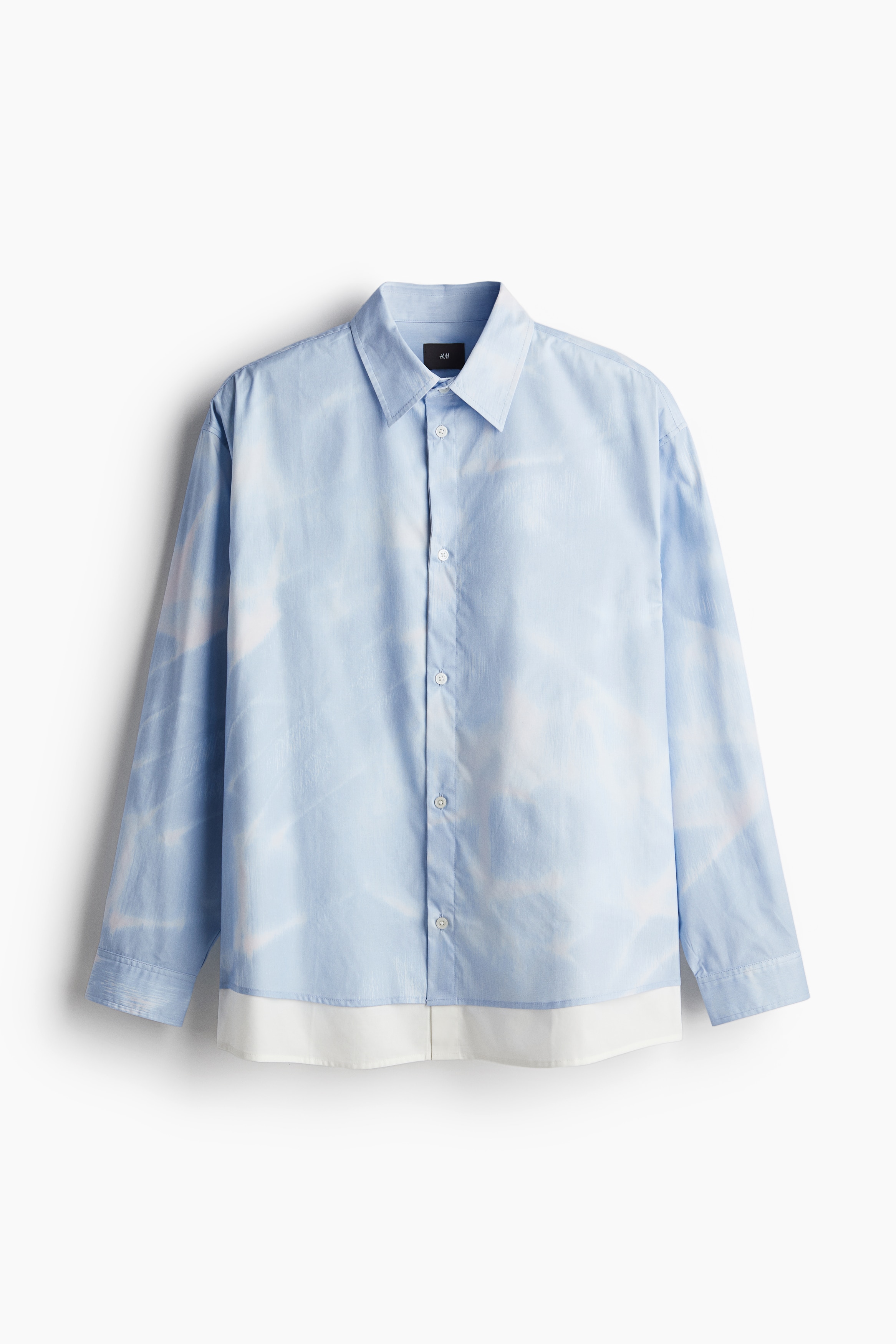 단색의 이너 레이어, 패턴이 있는 겉면 레이어로 마감된 부드러운 소재의 셔츠. 턴다운 칼라. 버튼단이 있는 클래식 프런트 스타일. 뒷면 요크. 플래킷과 링크 버튼이 있는 긴소매. 소맷단 버튼. 넉넉하지만 오버사이즈보다는 약간 피트되는 루즈핏 실루엣. 이미지