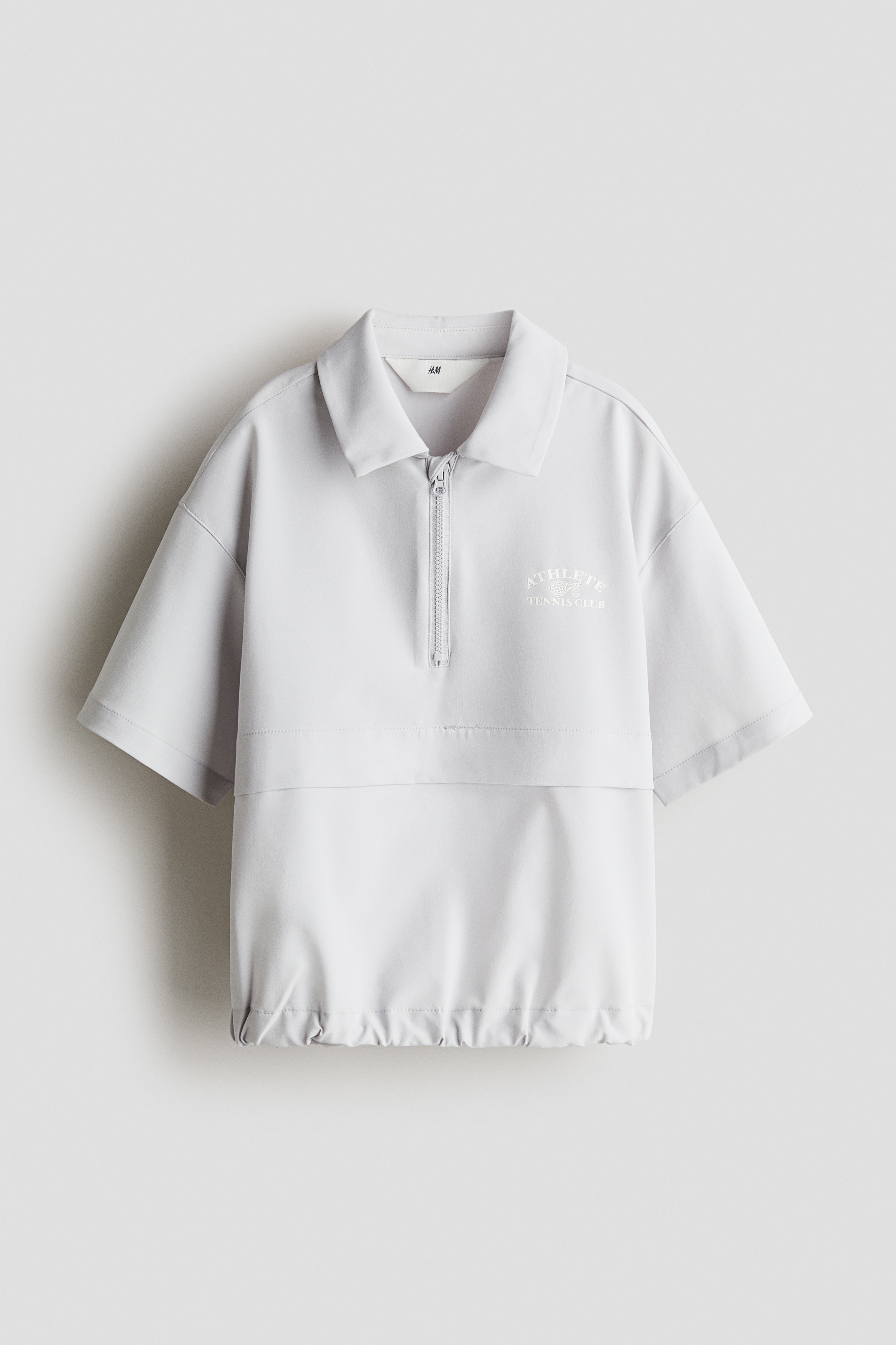 부드러운 우븐 소재의 프린트 폴로셔츠. 턴다운 칼라. 턱 부분에 쓸림 방지 덮개가 있는 상단 지퍼. 반소매. 드롭 숄더. 신축성 아랫단. 이미지