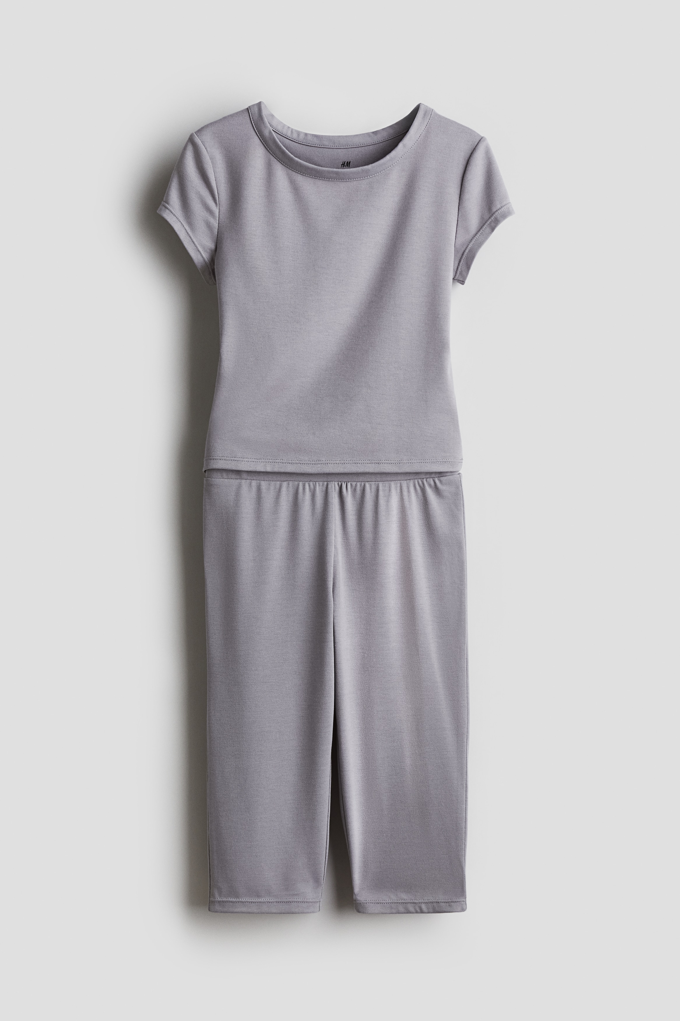 매우 부드러운 저지 소재의 탑 & 7부 레깅스 세트. 탑 - 반소매, 라운드넥. 레깅스 - 신축성 허릿단. 이미지