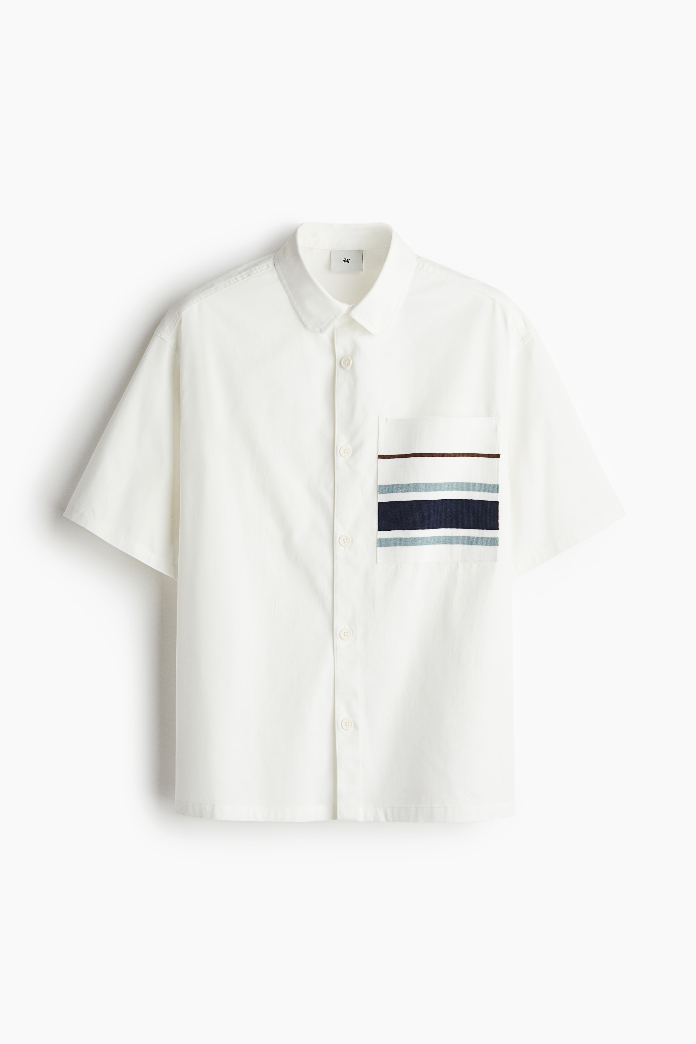 코튼 소재의 반소매 셔츠. 니트로 마감된 가슴 포켓. 루즈핏. 칼라 디테일. 버튼단이 없는 프렌치 프런트 스타일. 드롭 숄더. 스트레이트 헴라인. 이미지